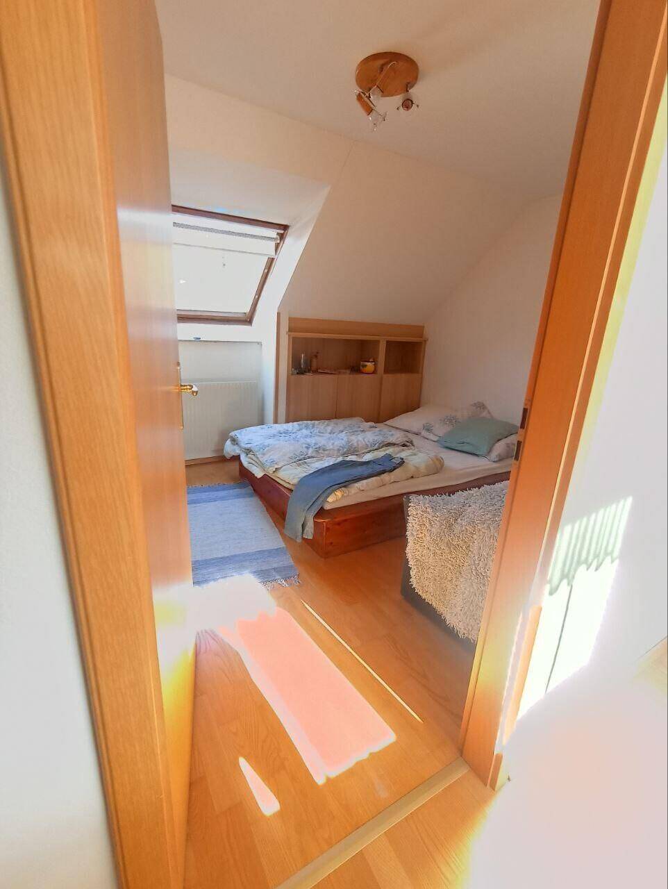 Gemütliches Schlafzimmer im Dachgeschoss mit Holzboden und einem Dachfenster für Tageslicht.