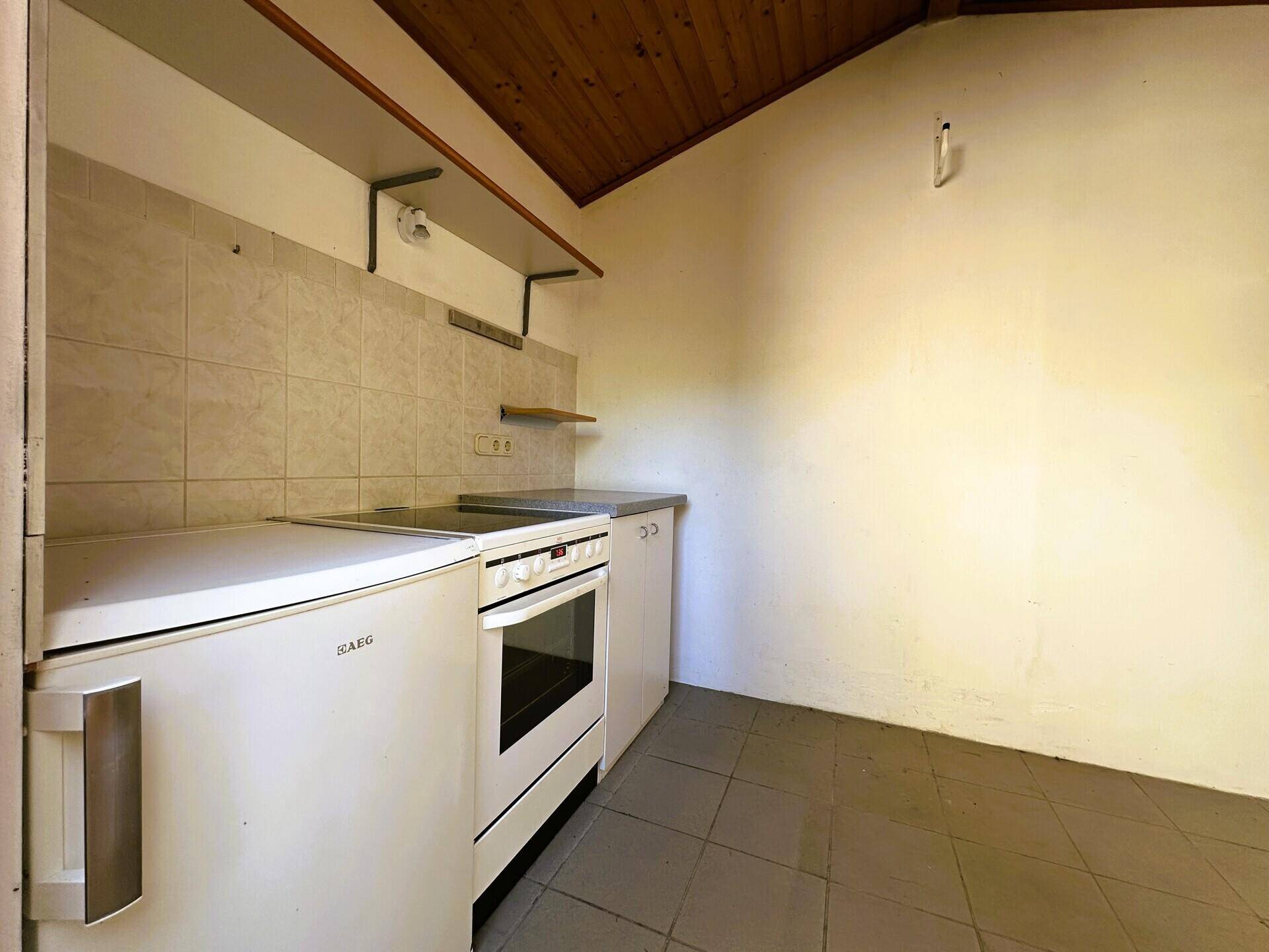 Einfache Küchenzeile mit Herd, Kühlschrank und Spüle in einem Abstellraum.