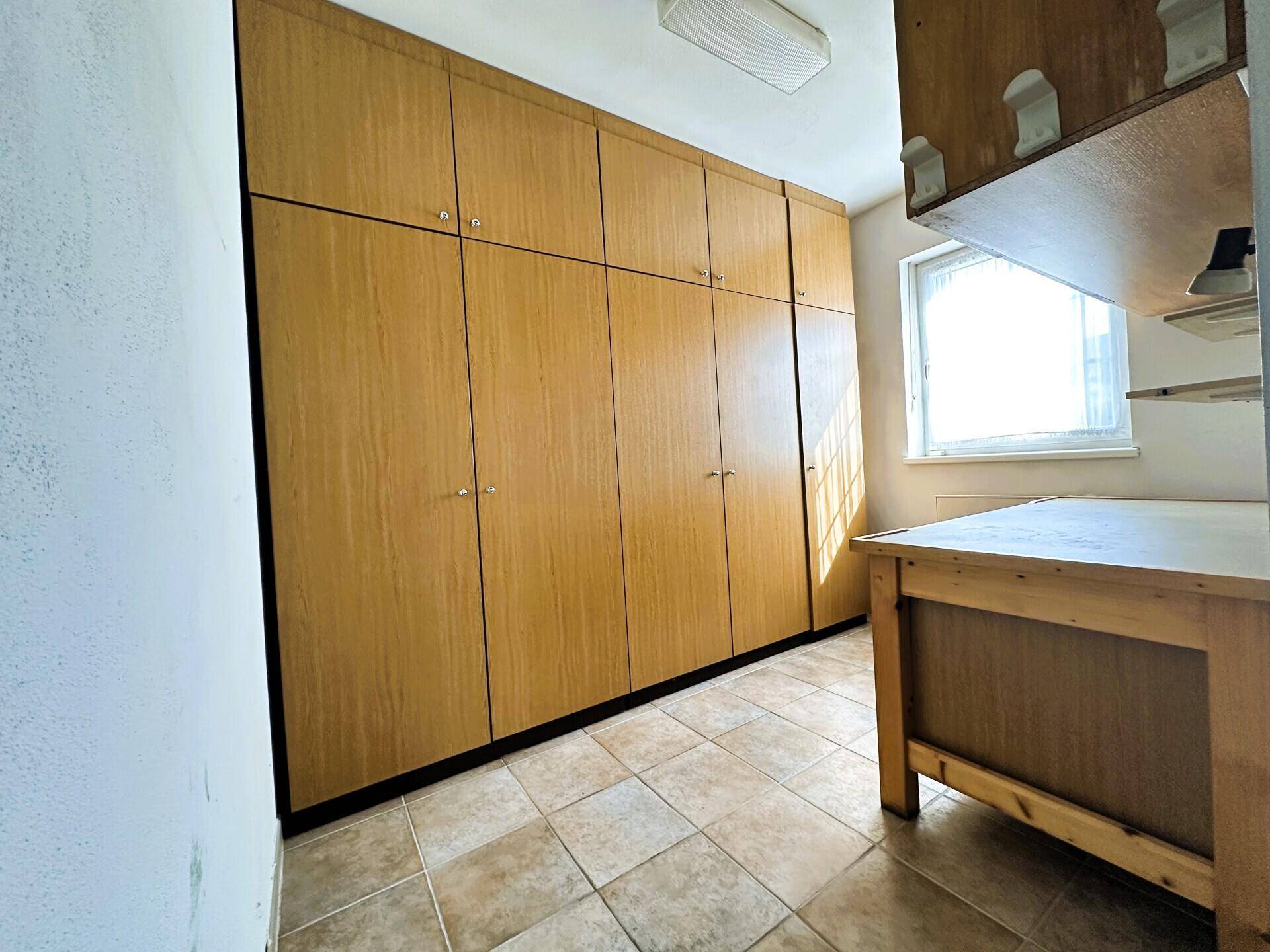 Geräumiger Abstellraum mit Einbauschränken und Fenster.