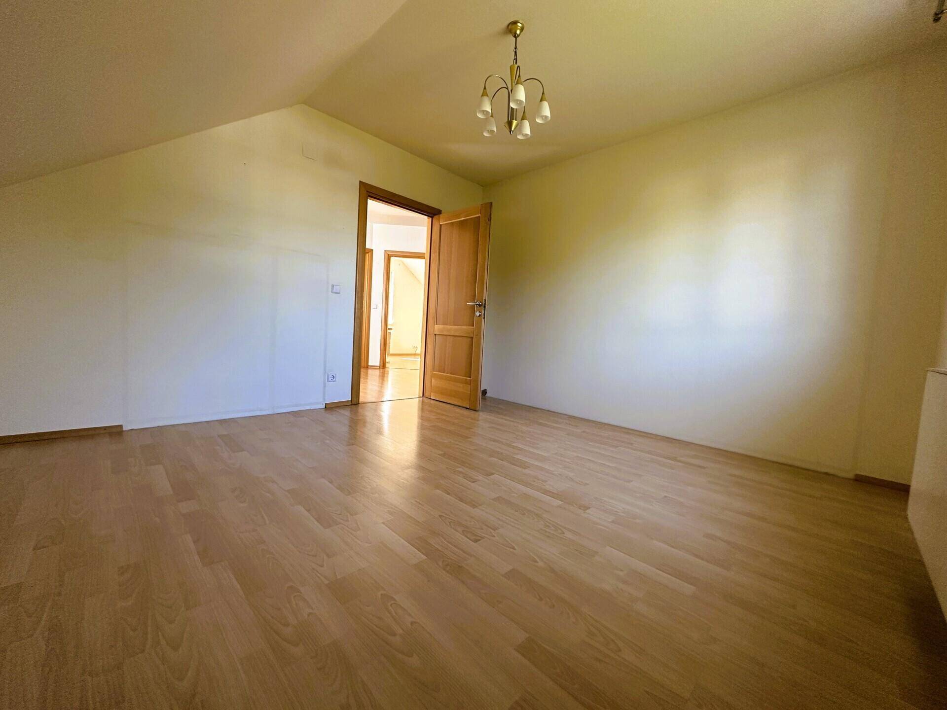 Geräumiges Schlafzimmer im Dachgeschoss mit Holzparkettboden und Dachschrägen.