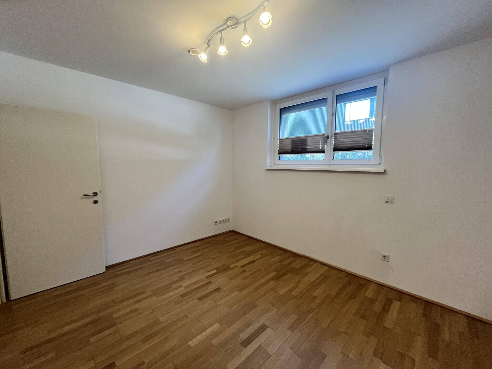 Geräumiges Schlafzimmer mit Parkettboden und Fenster, bietet viel Platz.
