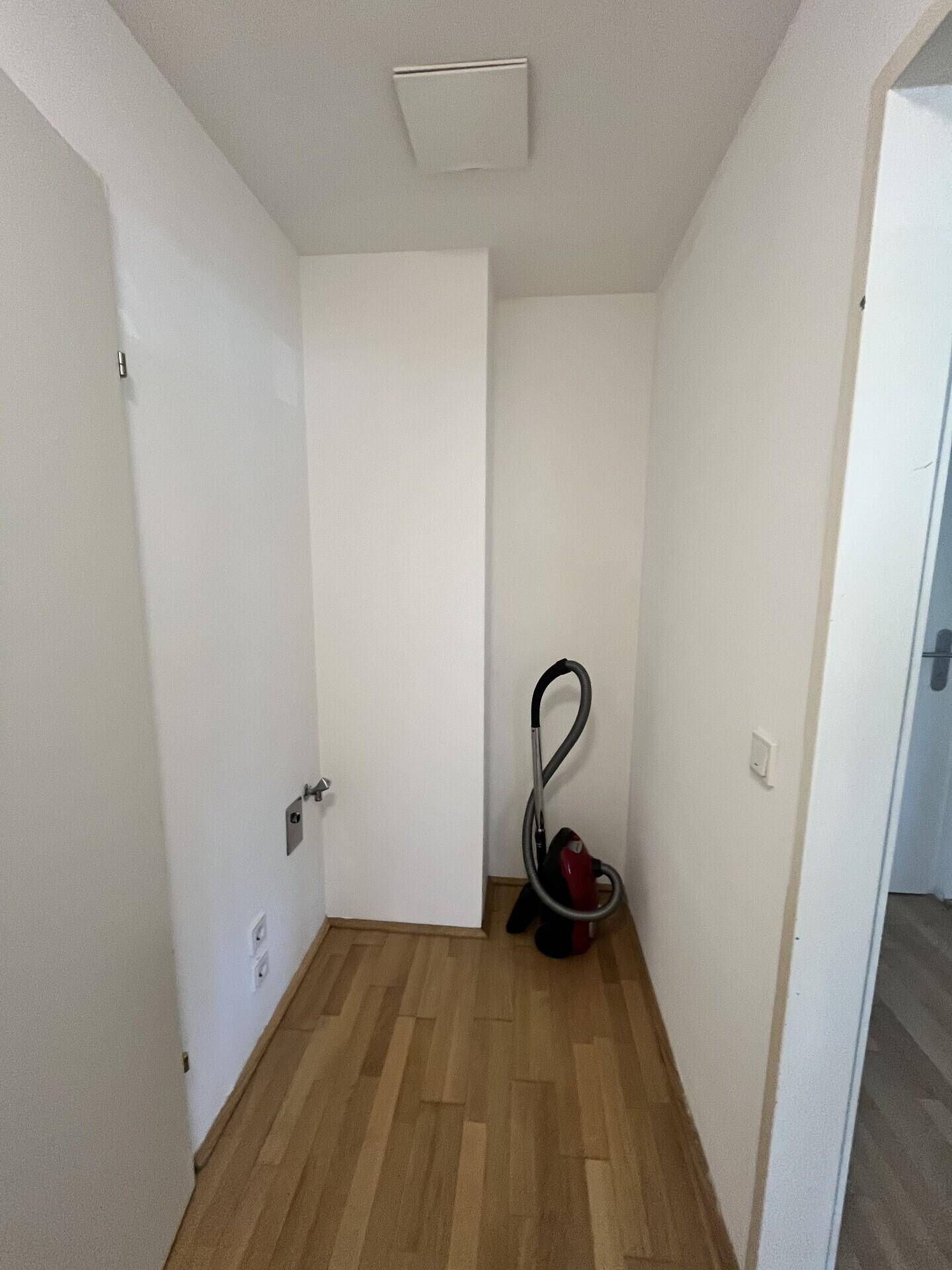 Praktischer Abstellraum mit Parkettboden und Anschlüssen für Waschmaschine.