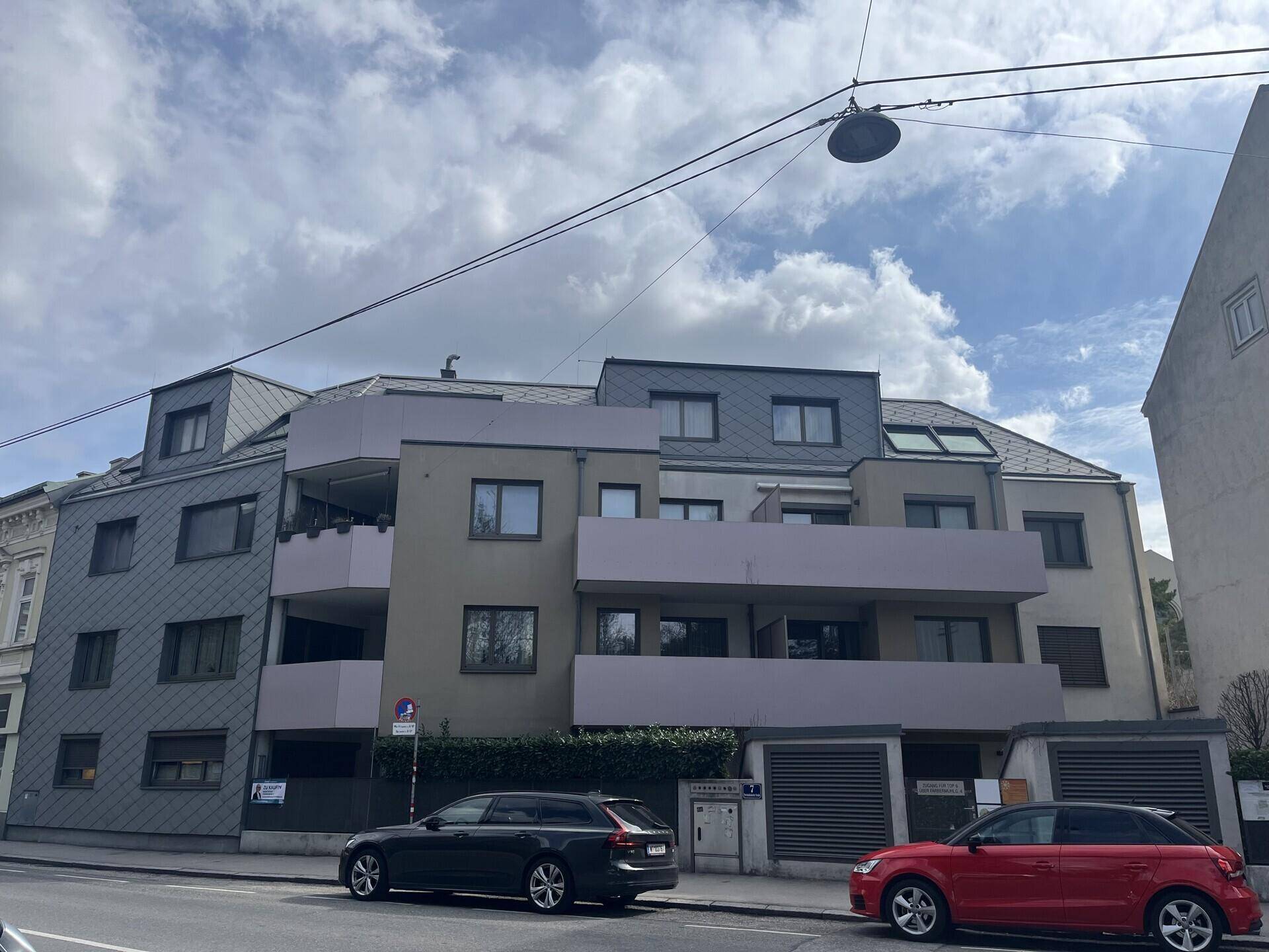 Modernes Mehrfamilienhaus mit Balkonen und Schieferdach in städtischer Umgebung.