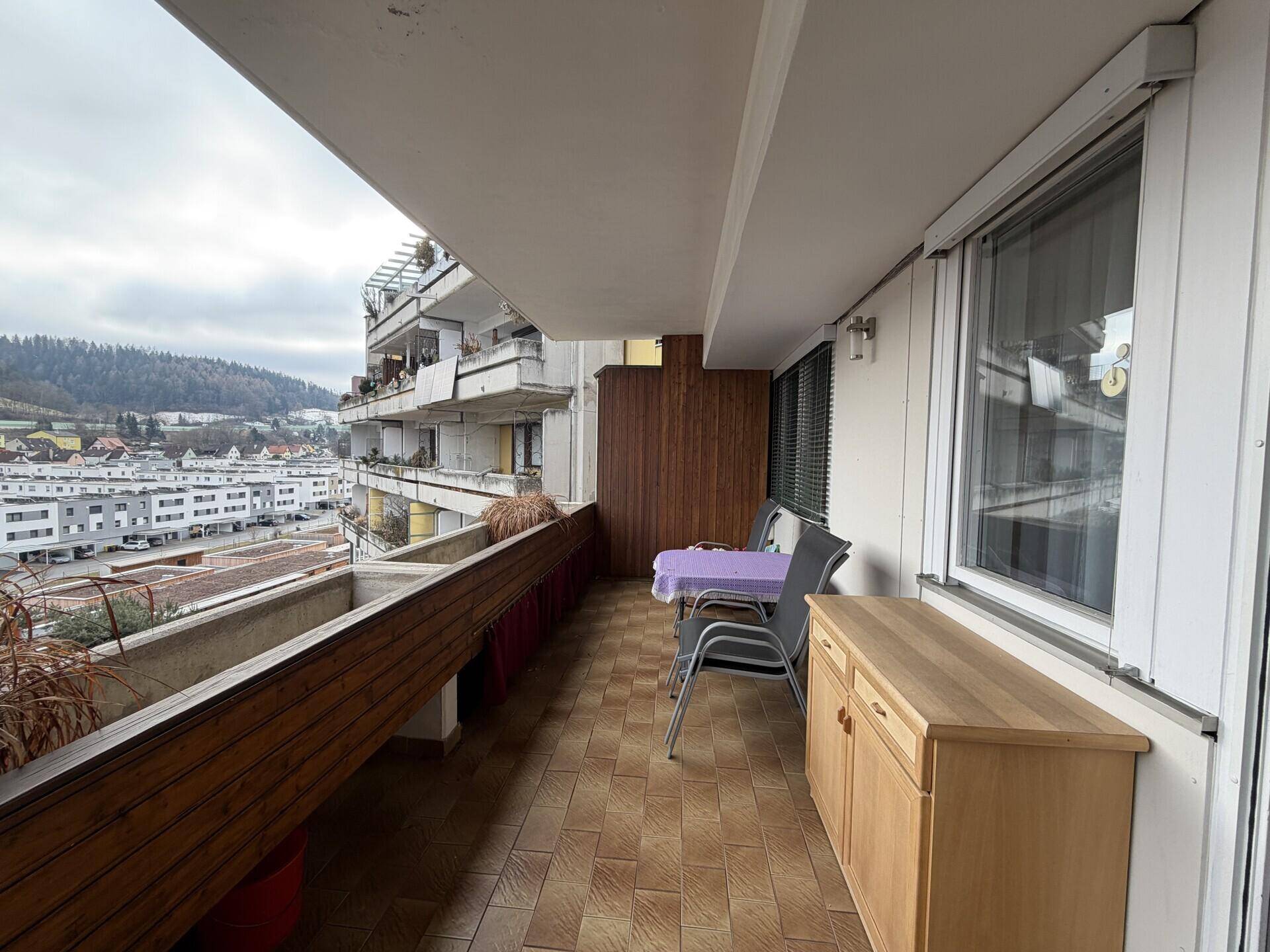 Geräumiger Balkon mit Fliesenboden, Sitzgelegenheiten und Blick auf die Umgebung.