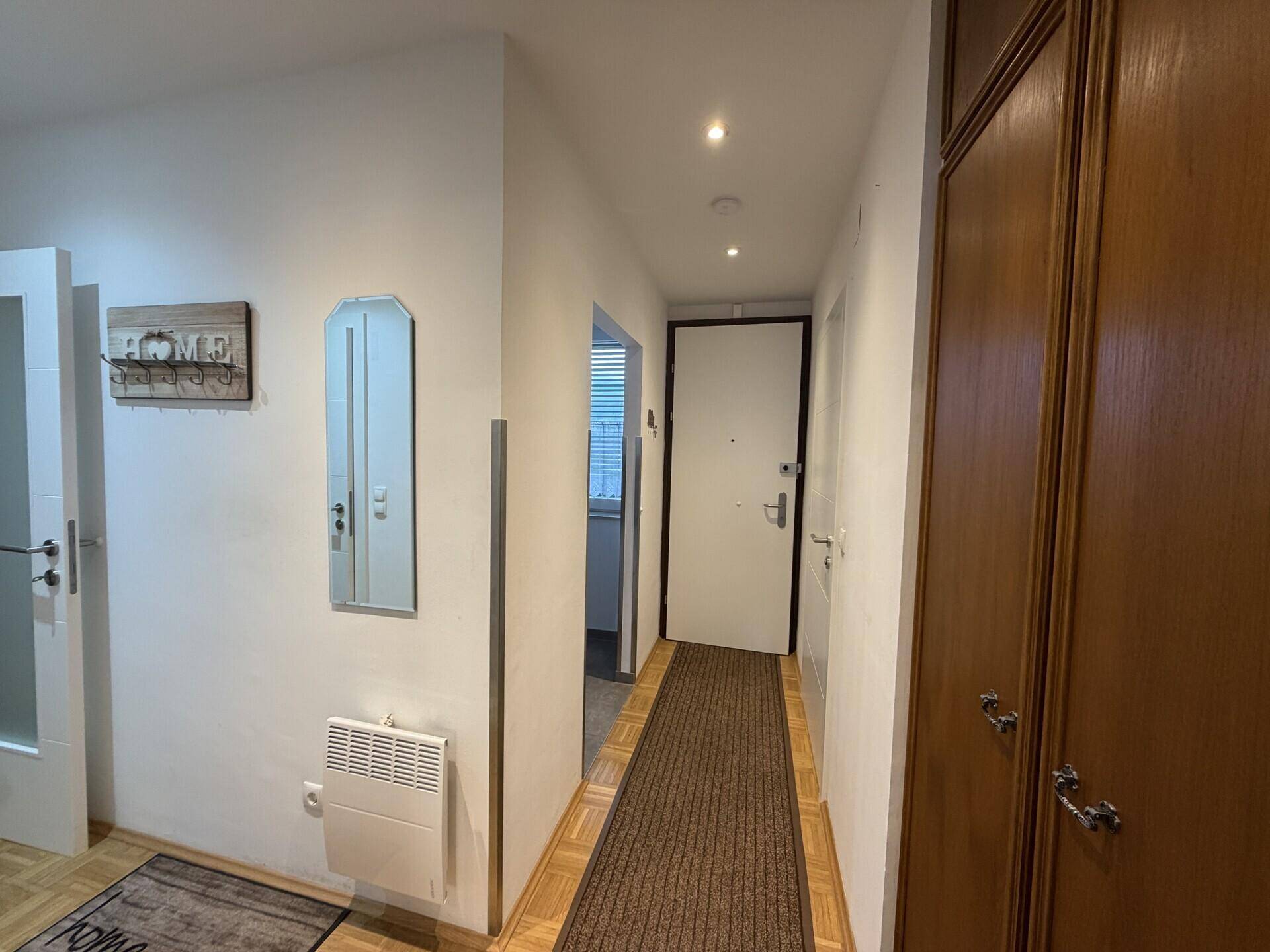 Heller Flur mit Parkettboden, Garderobe und Zugang zu verschiedenen Räumen.