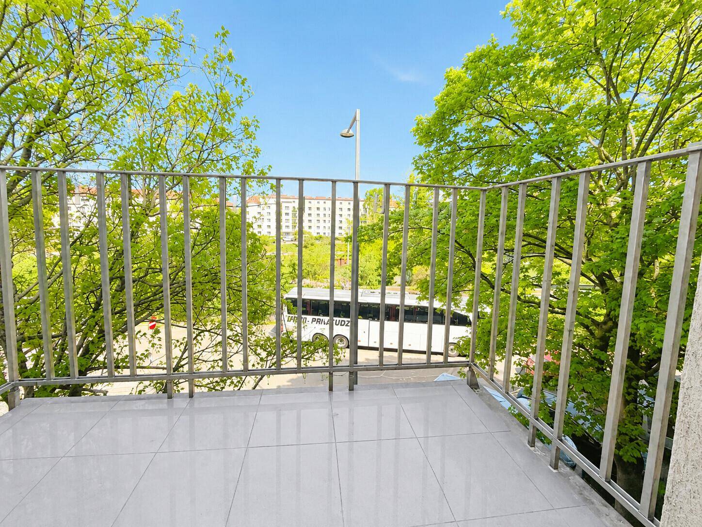 Balkon mit Metallgeländer und Blick ins Grüne sowie auf die Umgebung.
