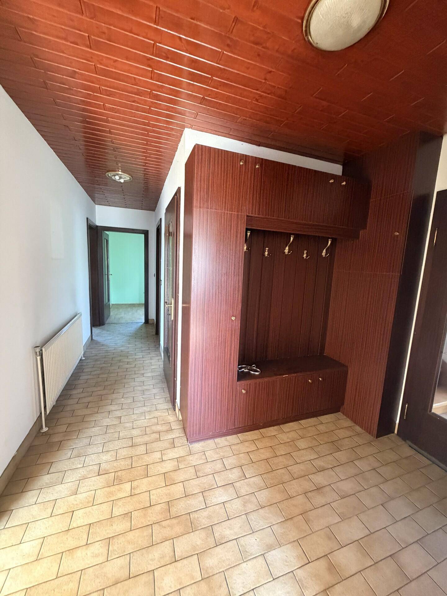 Geräumiger Flur mit Einbauschrank, Fliesenboden und Holzdecke.
