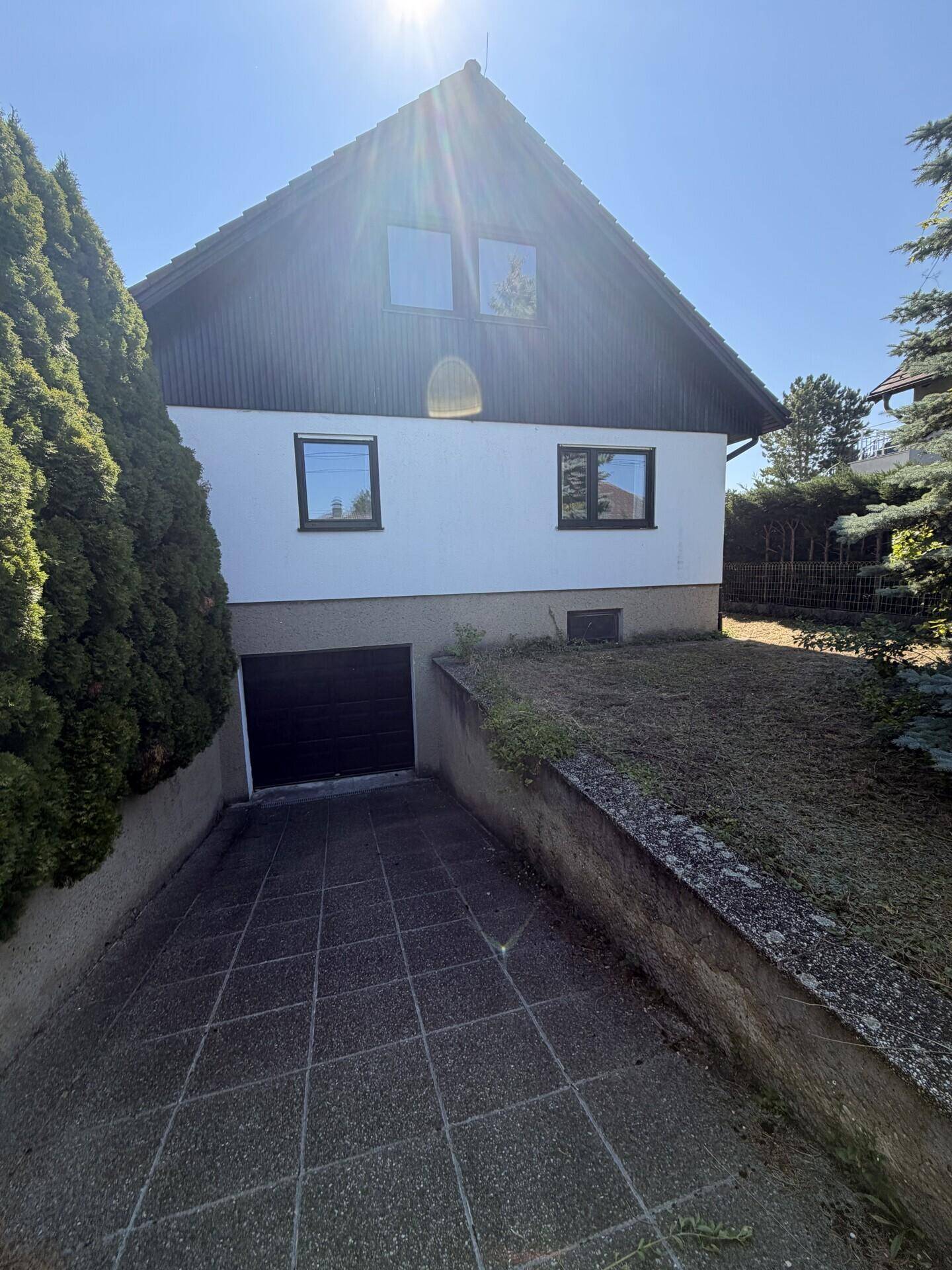 Vorderansicht des Hauses mit Garageneinfahrt und gepflastertem Zugangsbereich.