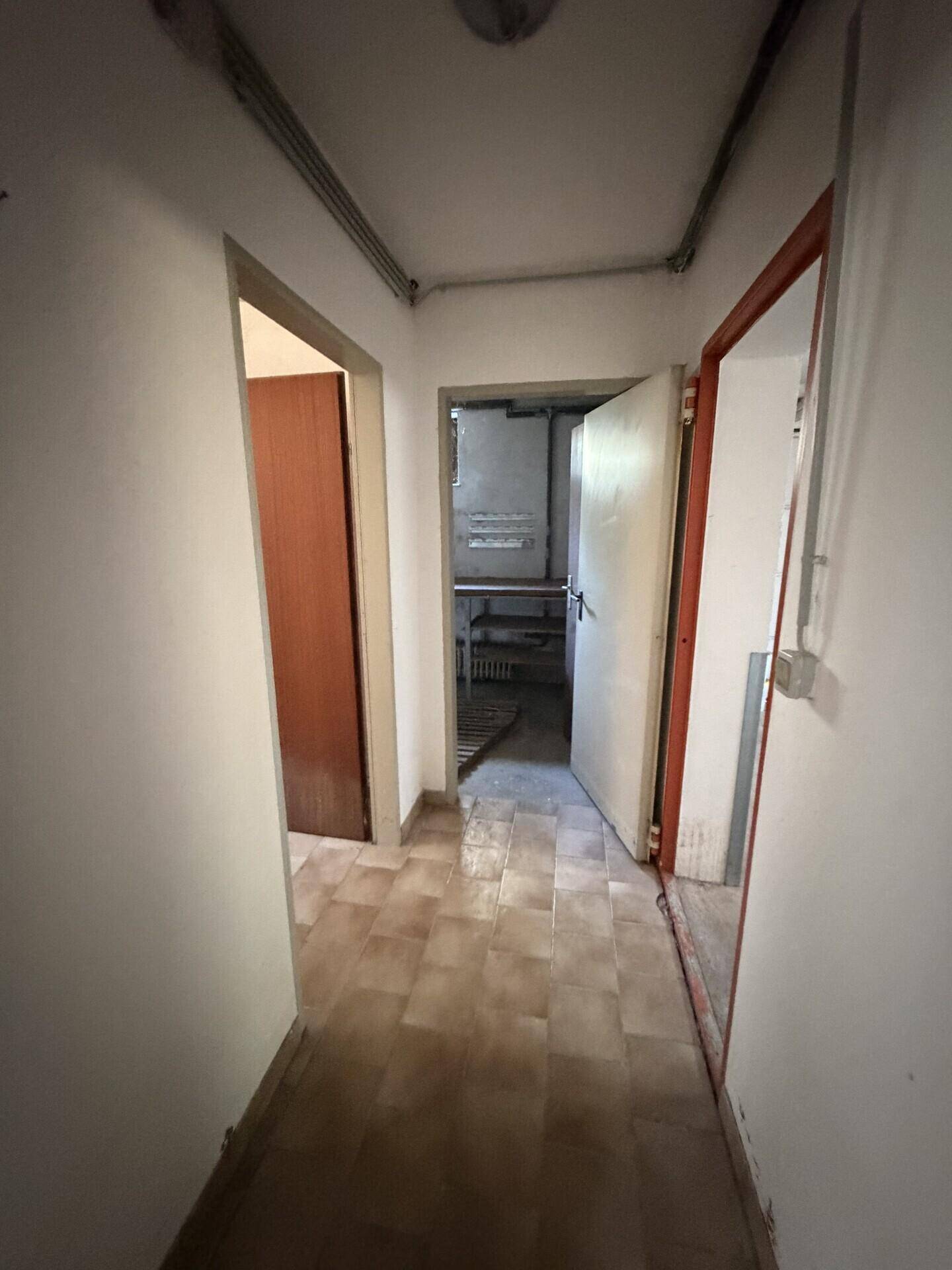 Kellerflur mit Fliesenboden und Zugang zu verschiedenen Kellerräumen.