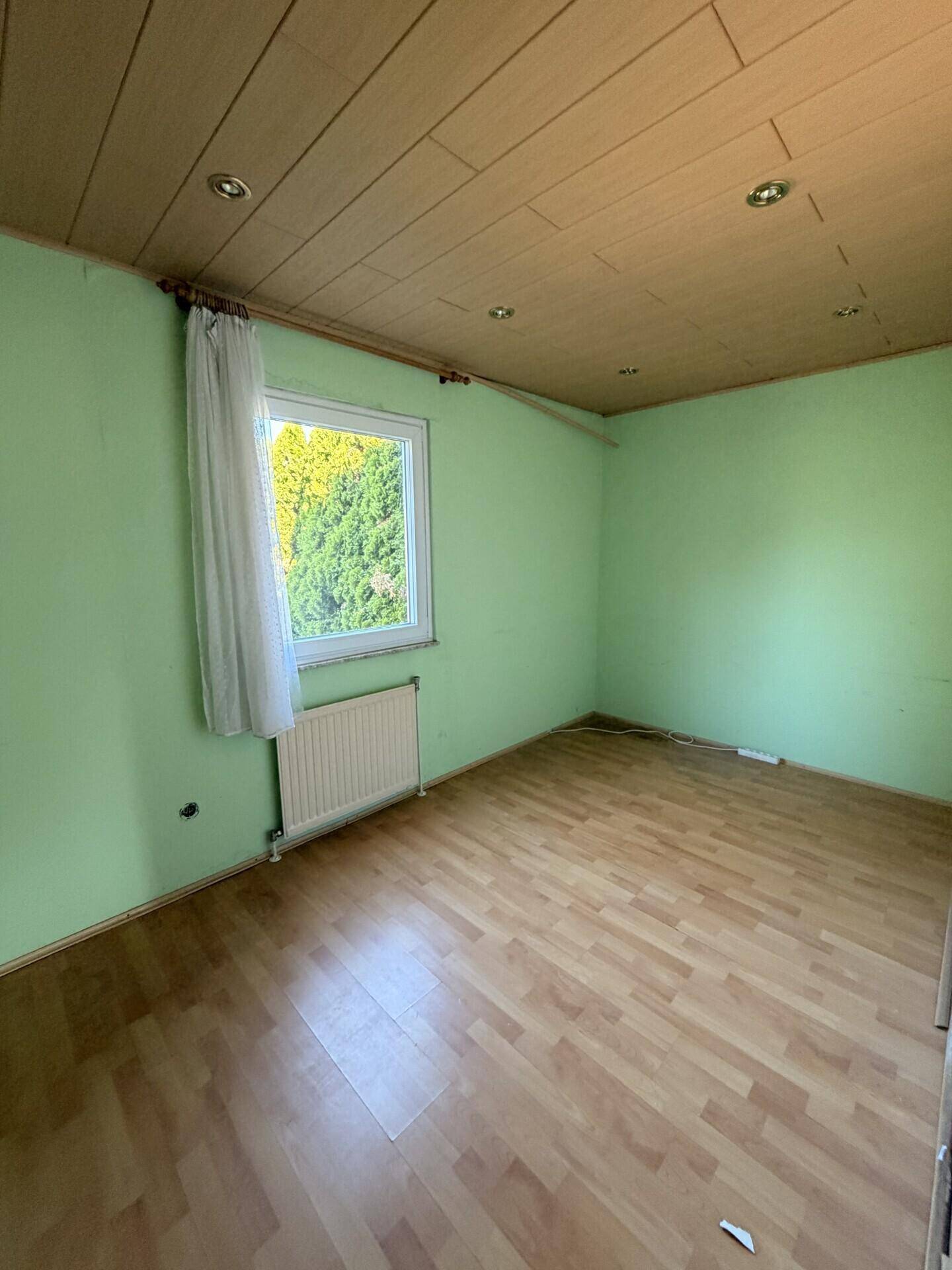 Kinderzimmer mit grün gestrichenen Wänden, Laminatboden und Holzdecke.