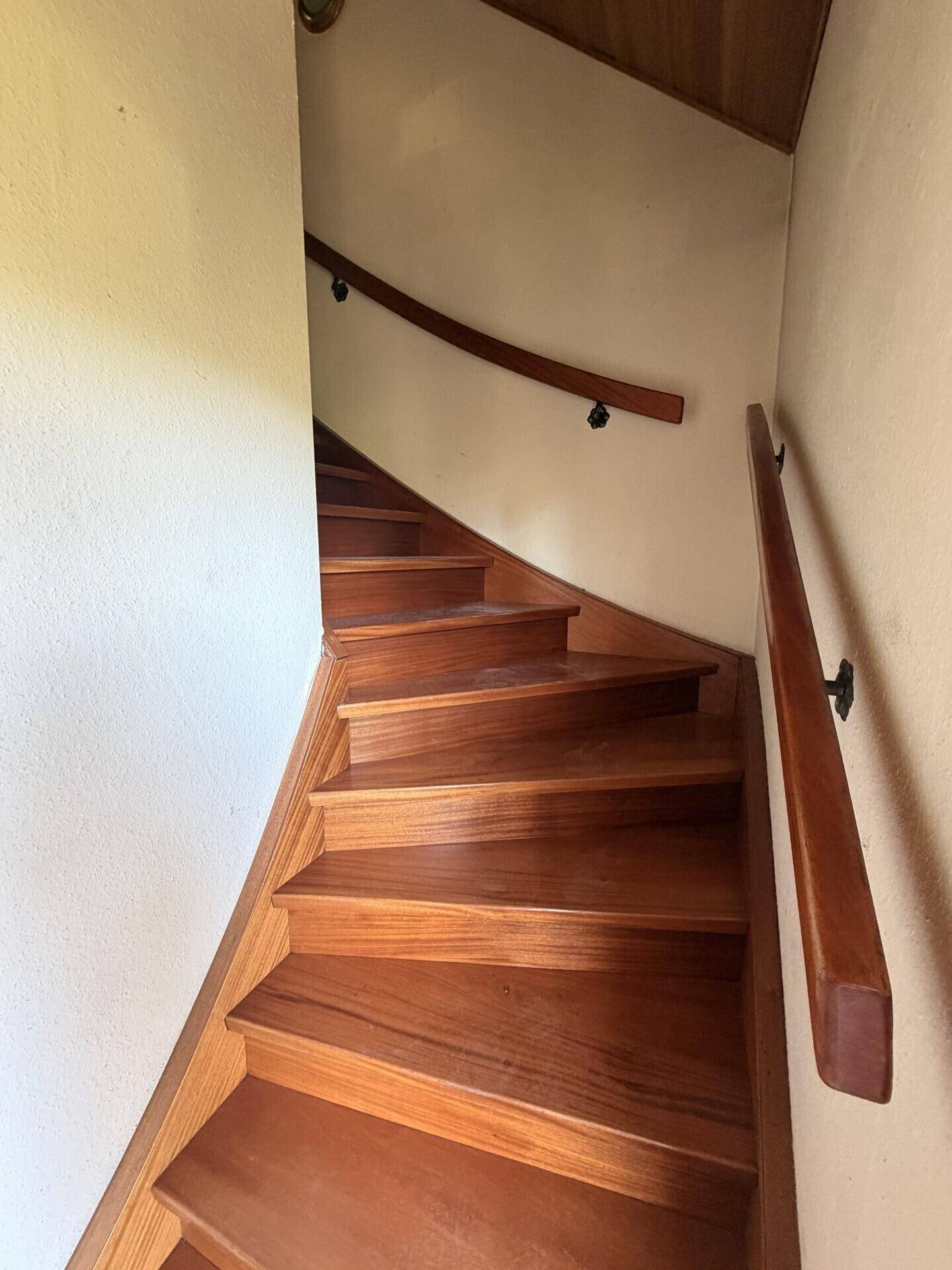 Holztreppe mit Handlauf, die in ein oberes Stockwerk führt.