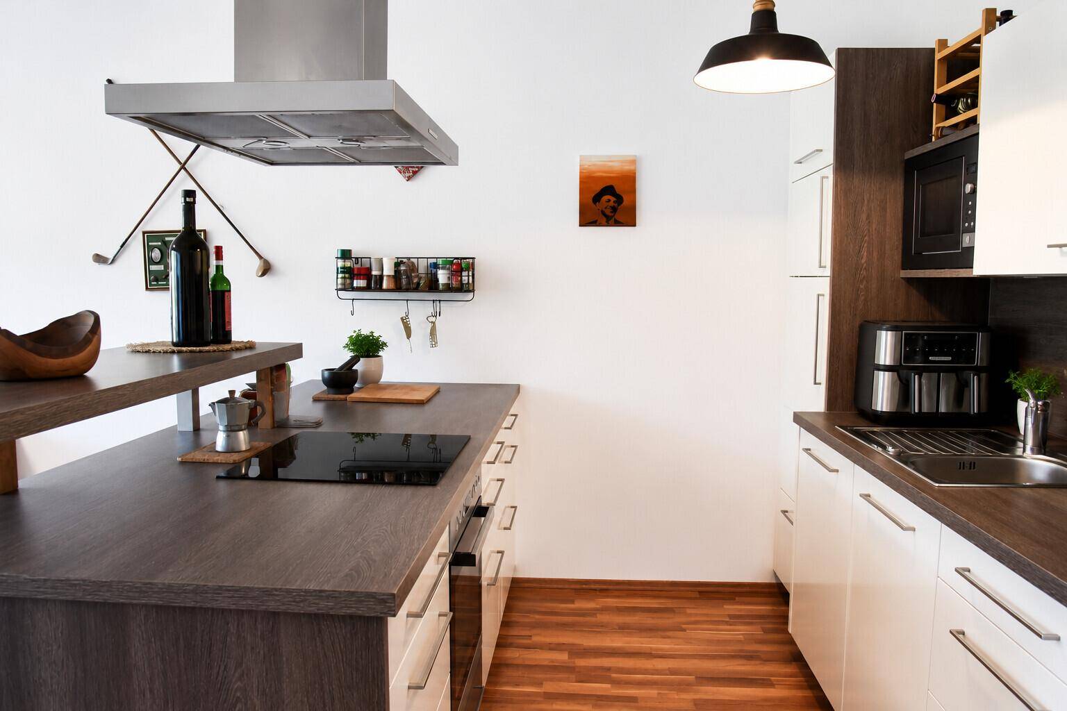Moderne Einbauküche mit Kochinsel, Induktionskochfeld und integrierten Geräten in hellem Design.