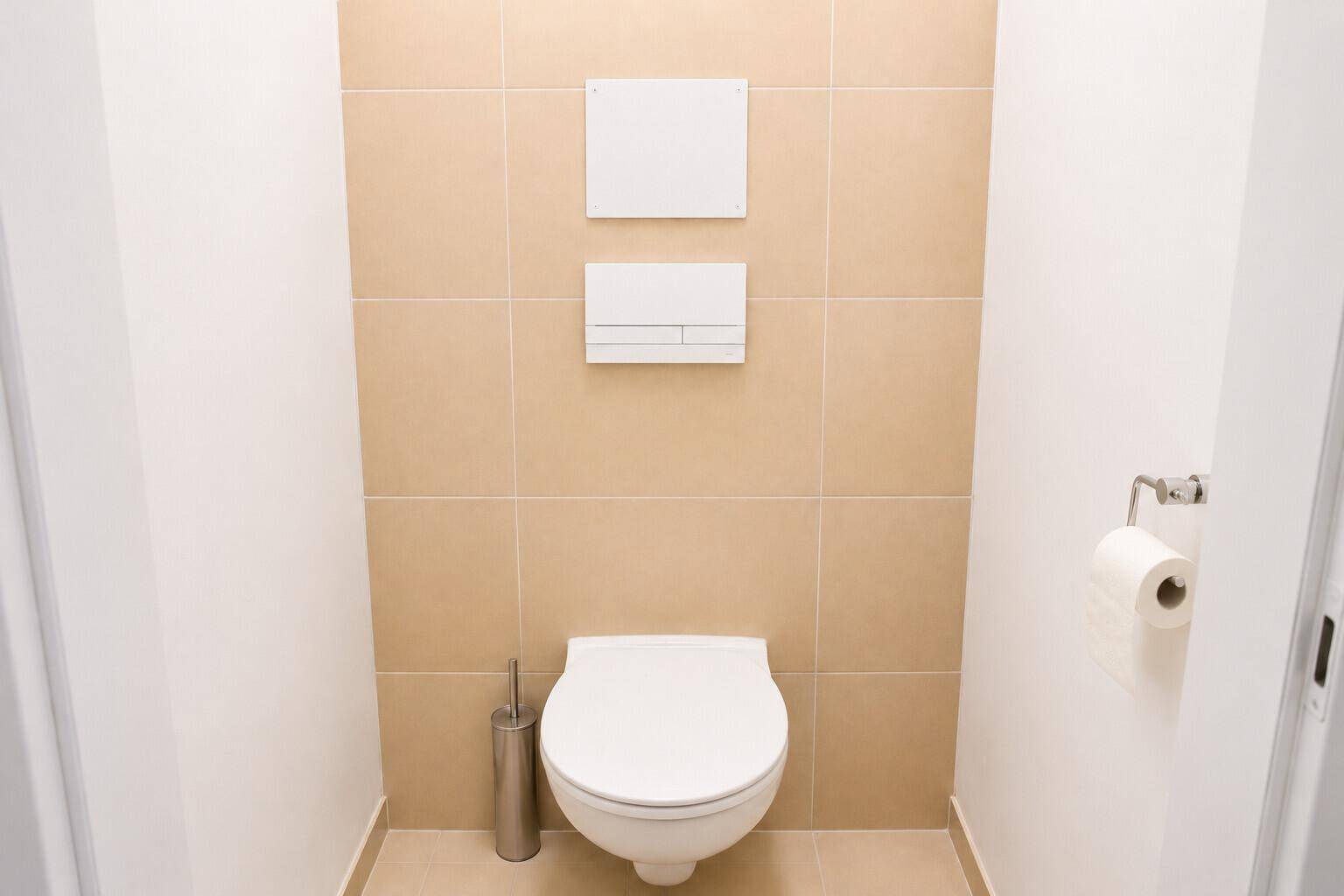Modernes separates WC mit wandhängender Toilette und beigefarbenen Fliesen an der Wand.