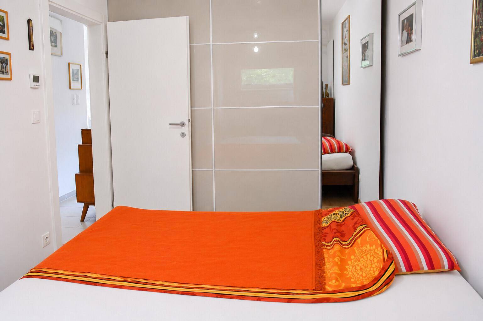 Schlafzimmer mit Doppelbett, farbenfroher Bettwäsche und integriertem Kleiderschrank.
