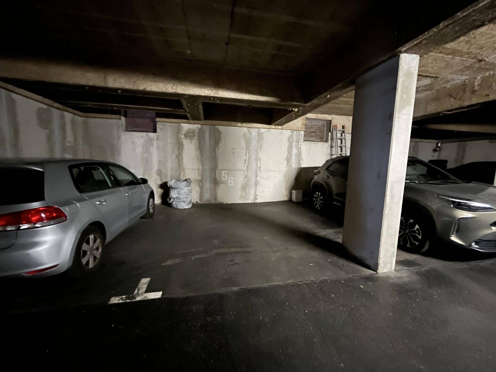 Tiefgarage mit Betonwänden und zwei geparkten Fahrzeugen, bietet sicheren Stellplatz.