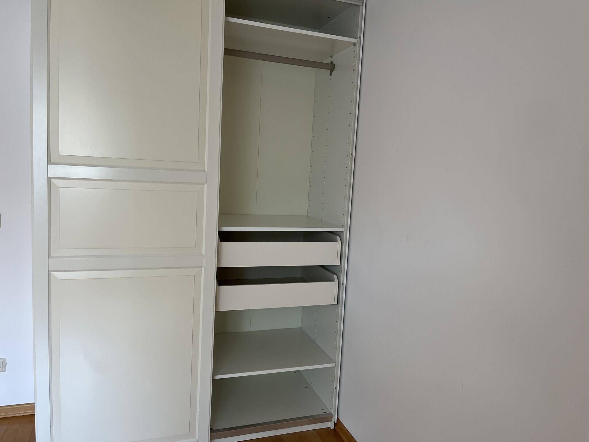 Kleiderschrank im Schlafzimmer mit offenen Fächern und Schubladen für zusätzlichen Stauraum.