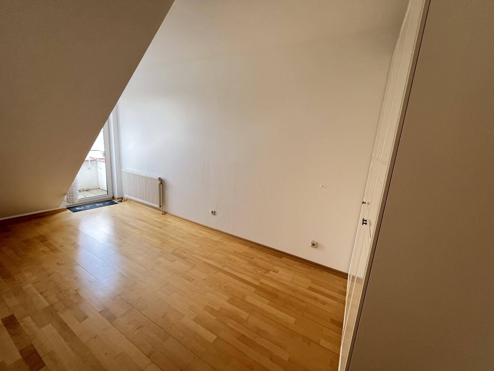 Helles Schlafzimmer im Dachgeschoss mit Parkettboden und Dachschräge, bereit zur Einrichtung.