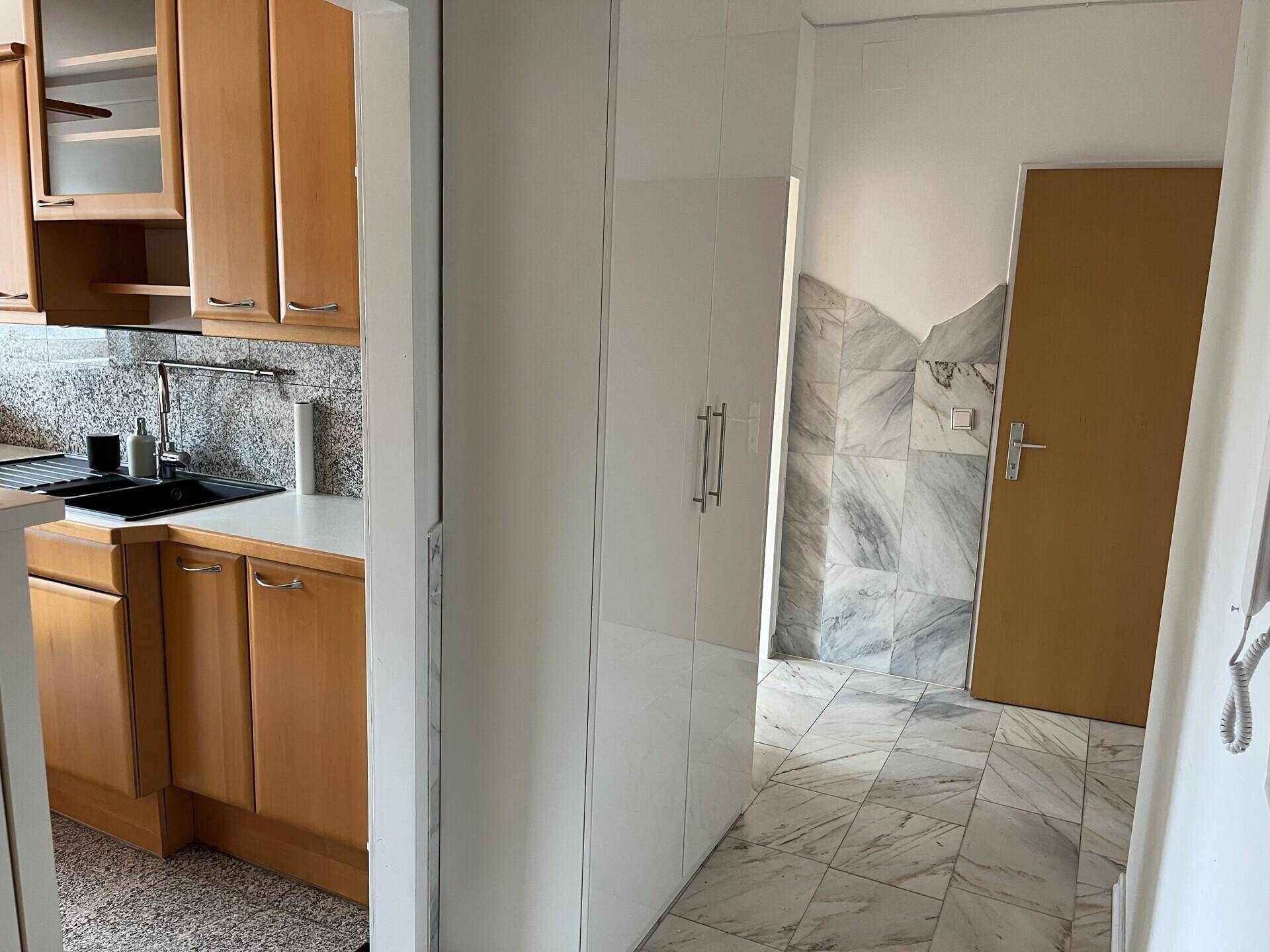 Flur mit Marmorfliesen und weißem Einbauschrank, angrenzend an die Küche.