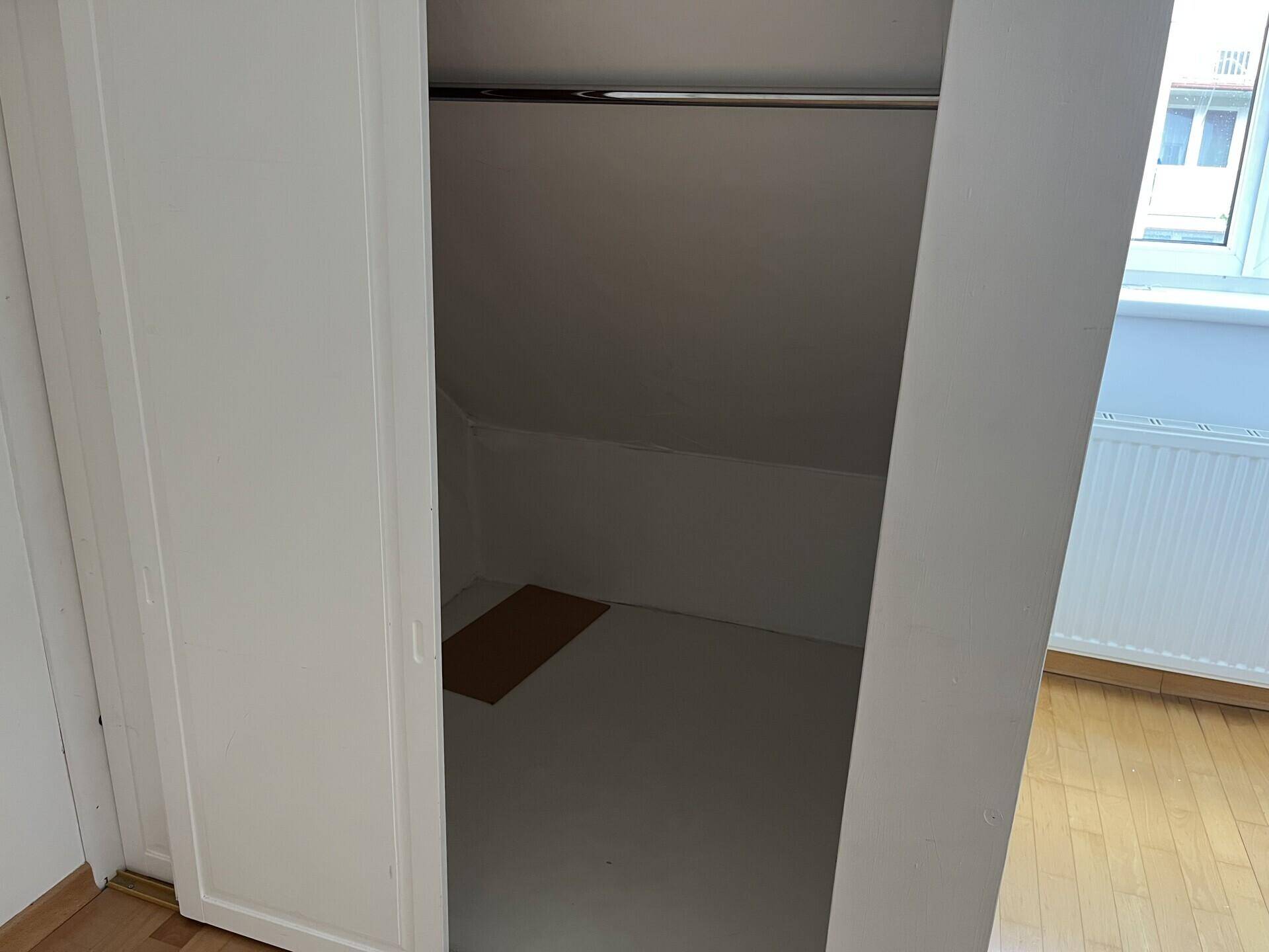 Offener Kleiderschrank im Schlafzimmer mit Stauraum unter der Dachschräge.