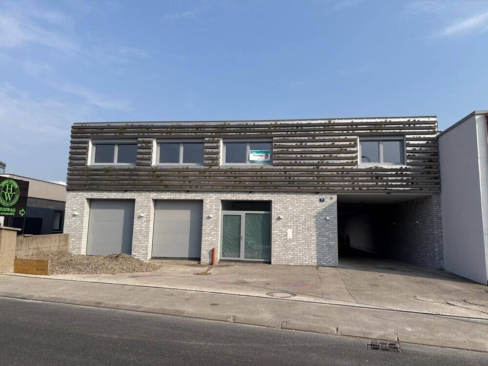 Modernes Geschäftsgebäude mit heller Ziegelfassade, horizontalen Lamellen und Garagentoren.