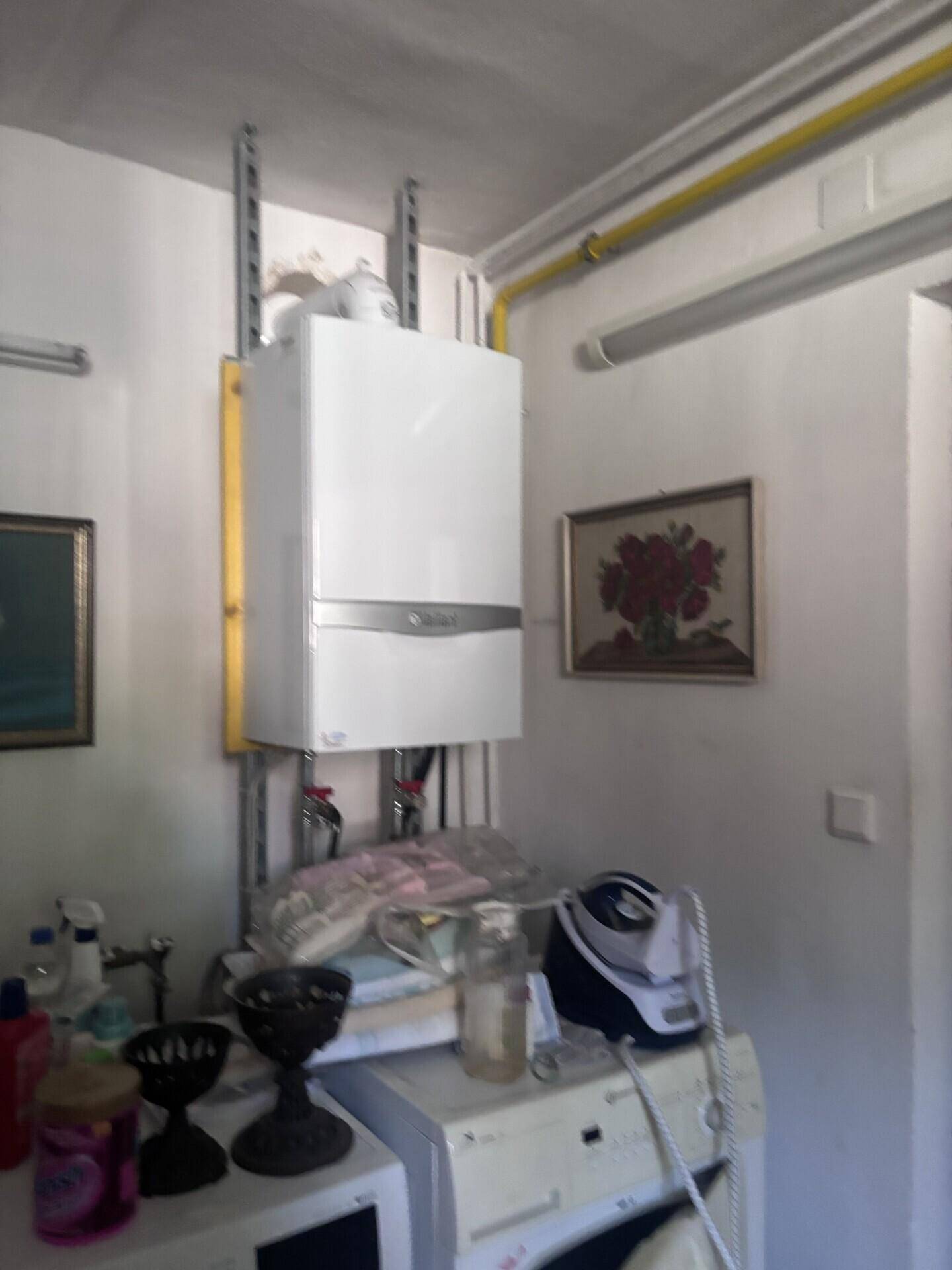 Hauswirtschaftsraum mit Heizungsanlage, Waschmaschine und Stauraum für Haushaltsgeräte.