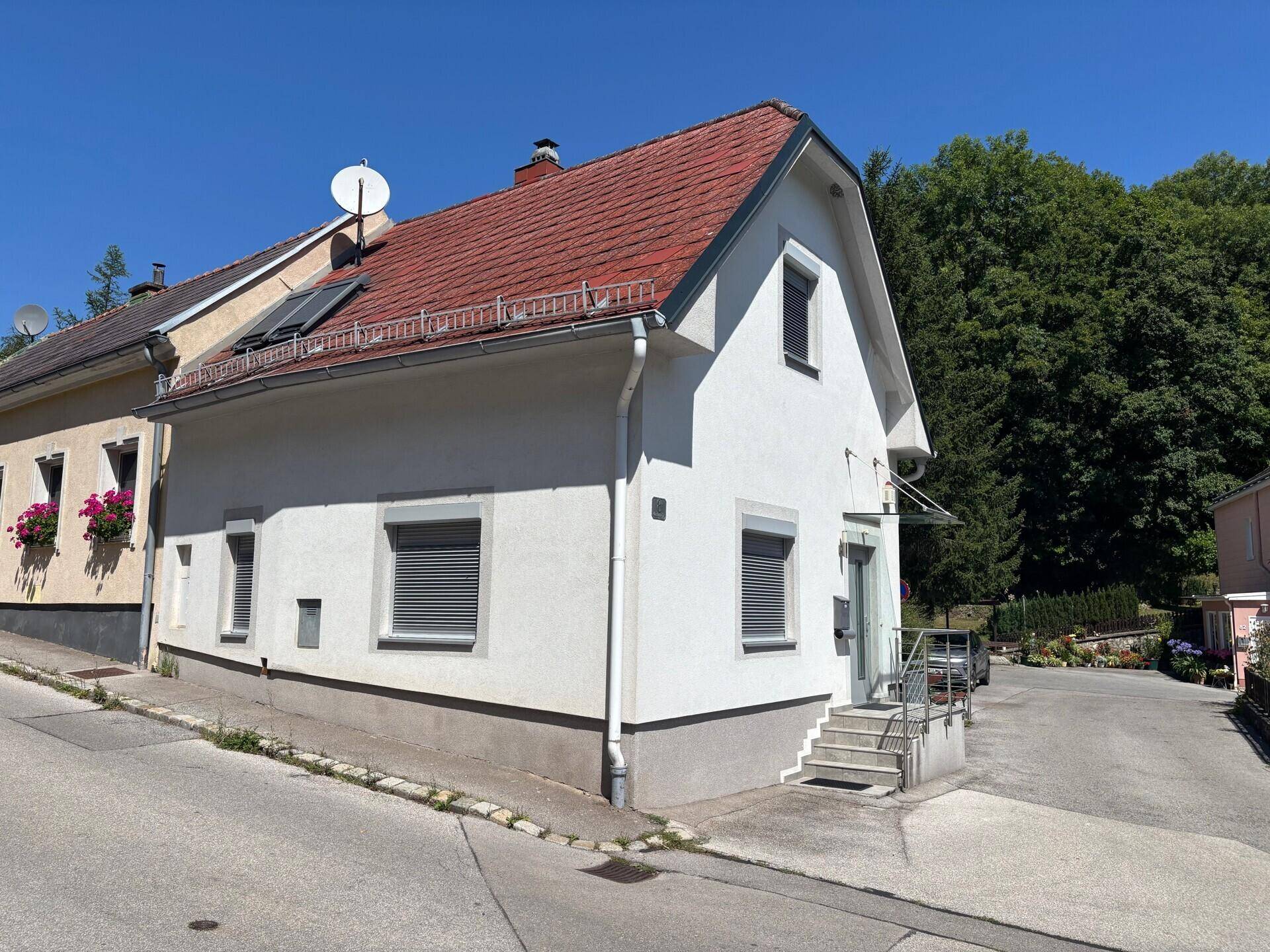 Seitenansicht des Hauses mit Satteldach, Rollläden und Solarpaneelen auf dem Dach.