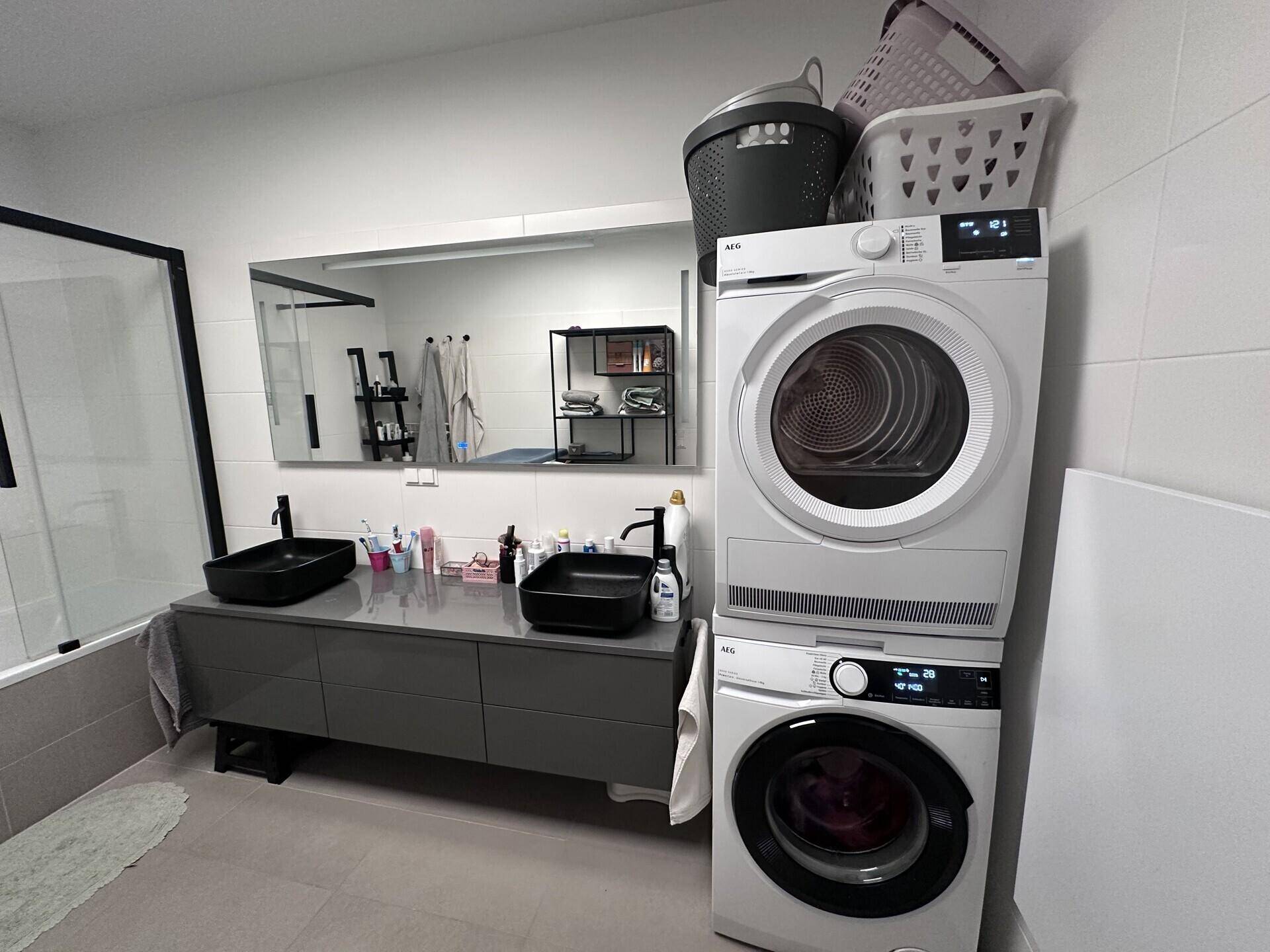 Badezimmer mit Waschmaschine, Trockner und modernem Doppelwaschbecken.