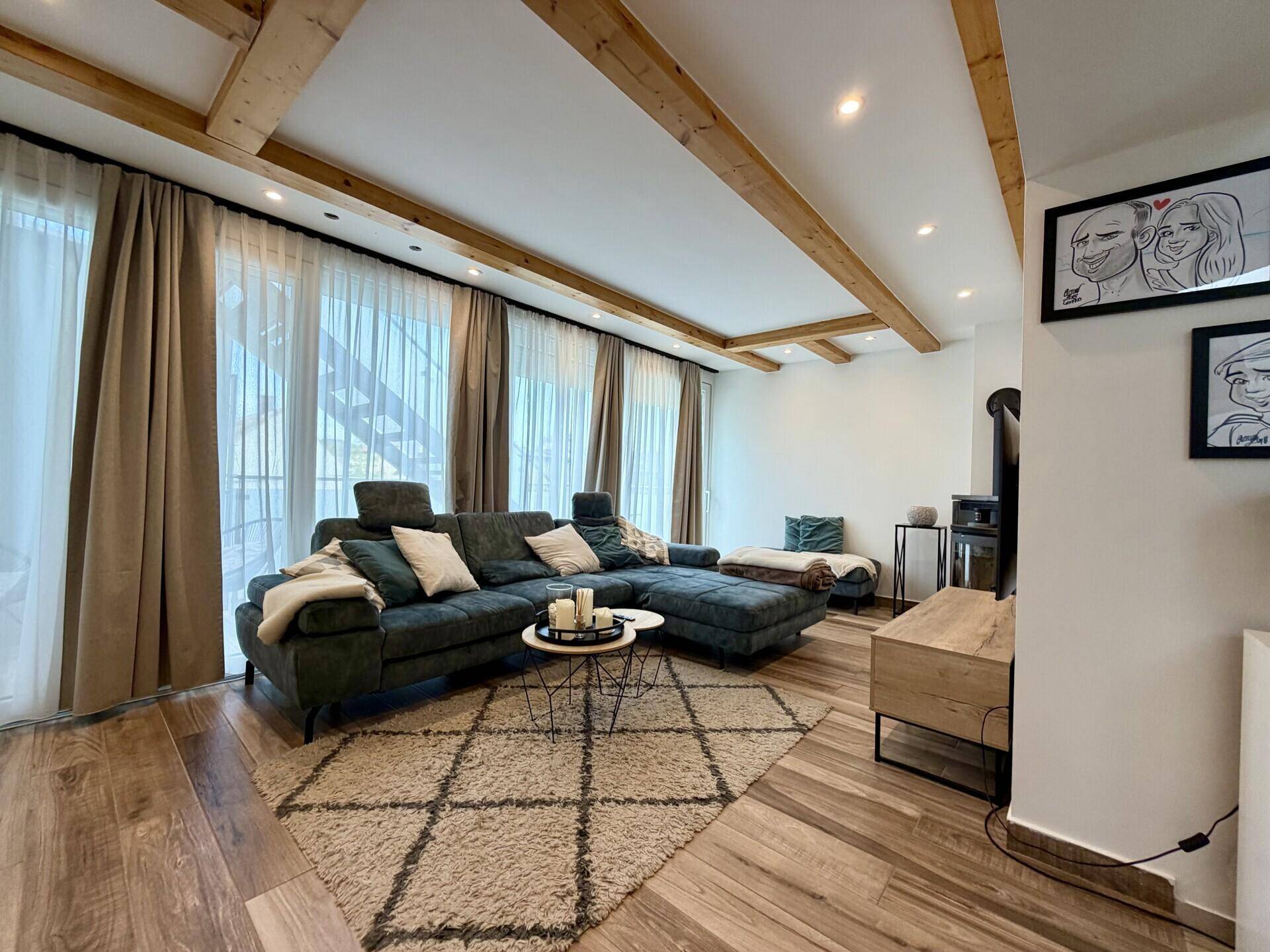 Gemütliches Wohnzimmer mit Holzbalken, Kaminofen und Zugang zu einem Außenbereich.