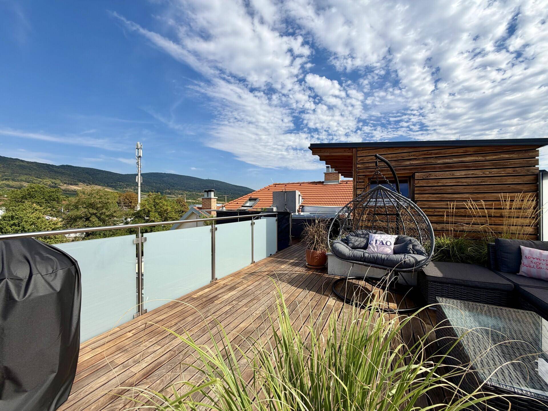 Dachterrasse mit Lounge-Bereich, Hängesessel und Blick auf die umliegende Landschaft.