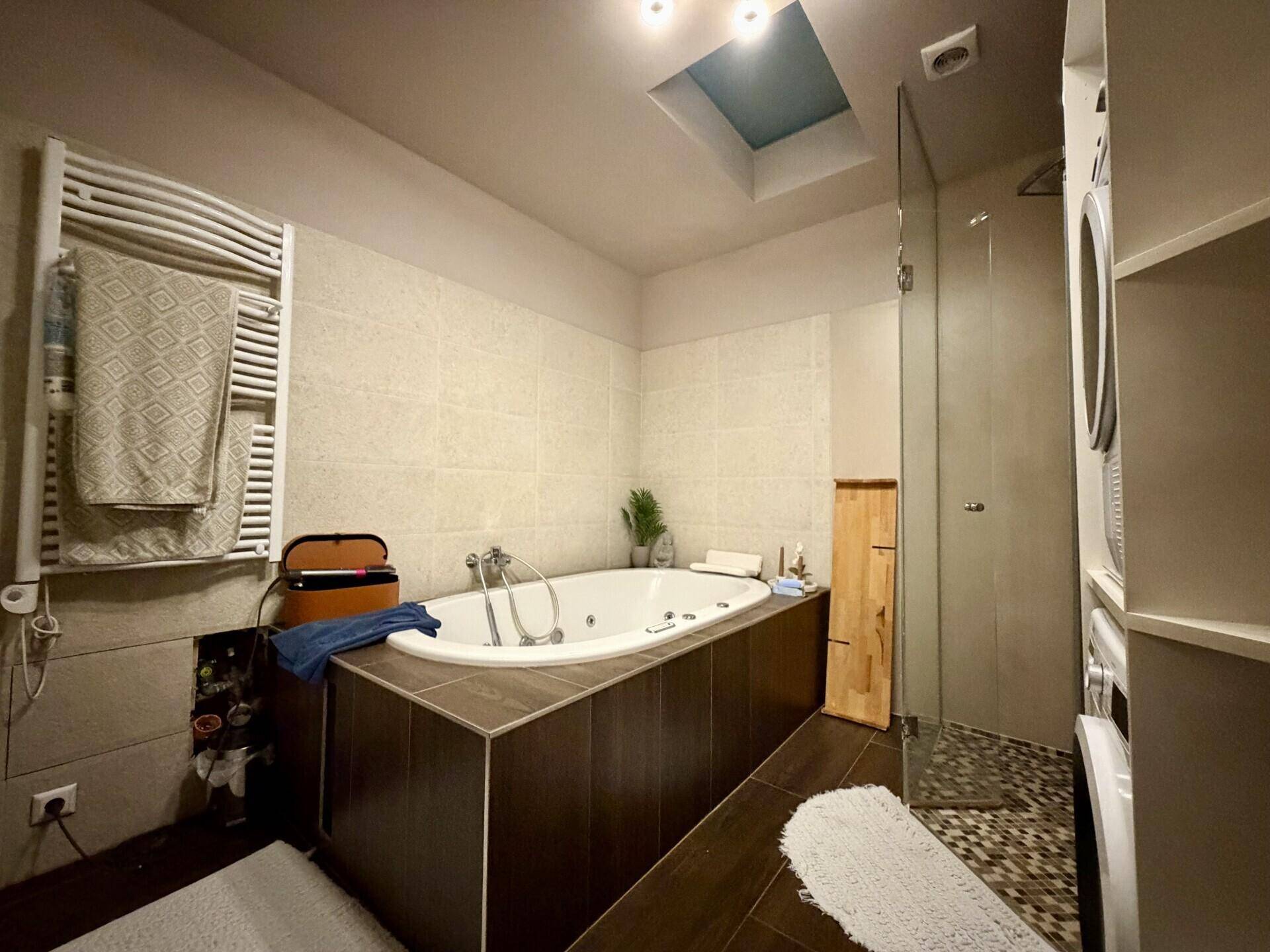 Badezimmer mit Whirlpool-Badewanne, Duschbereich und beheiztem Handtuchhalter.