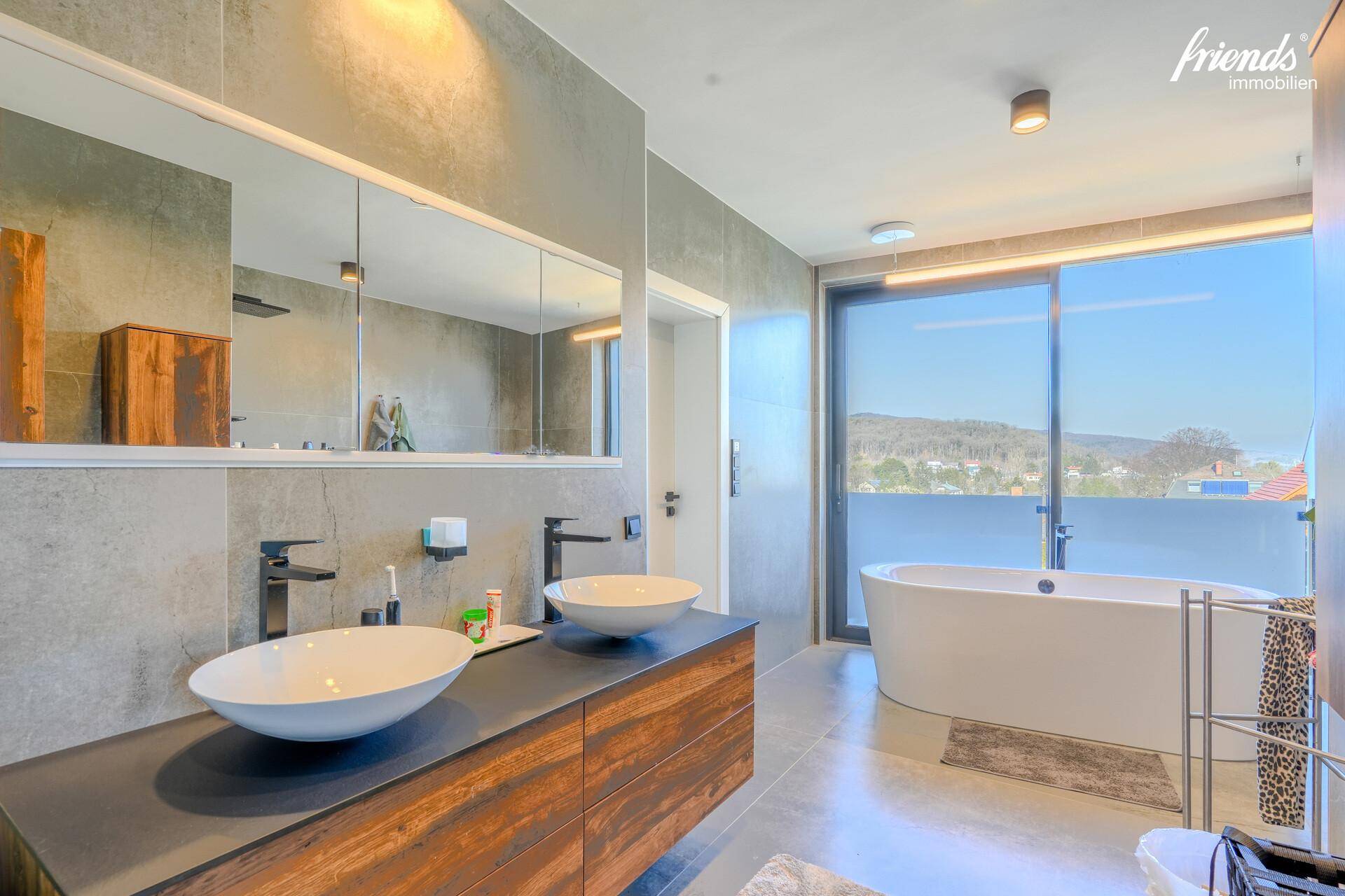 Modernes Badezimmer mit Doppelwaschbecken, freistehender Badewanne und Panoramablick.