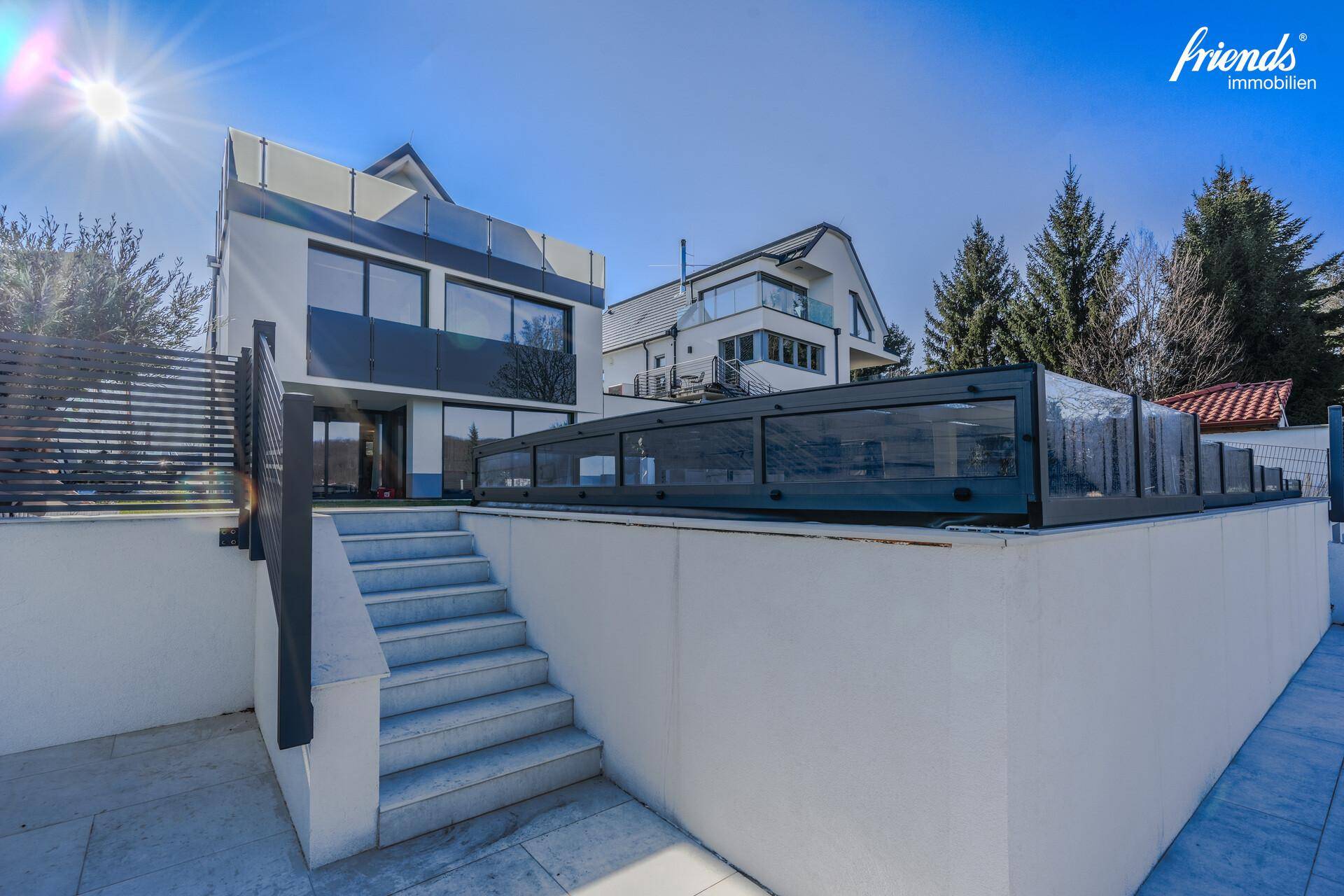 Moderne Architektur mit einem überdachten Poolbereich und Außentreppe.