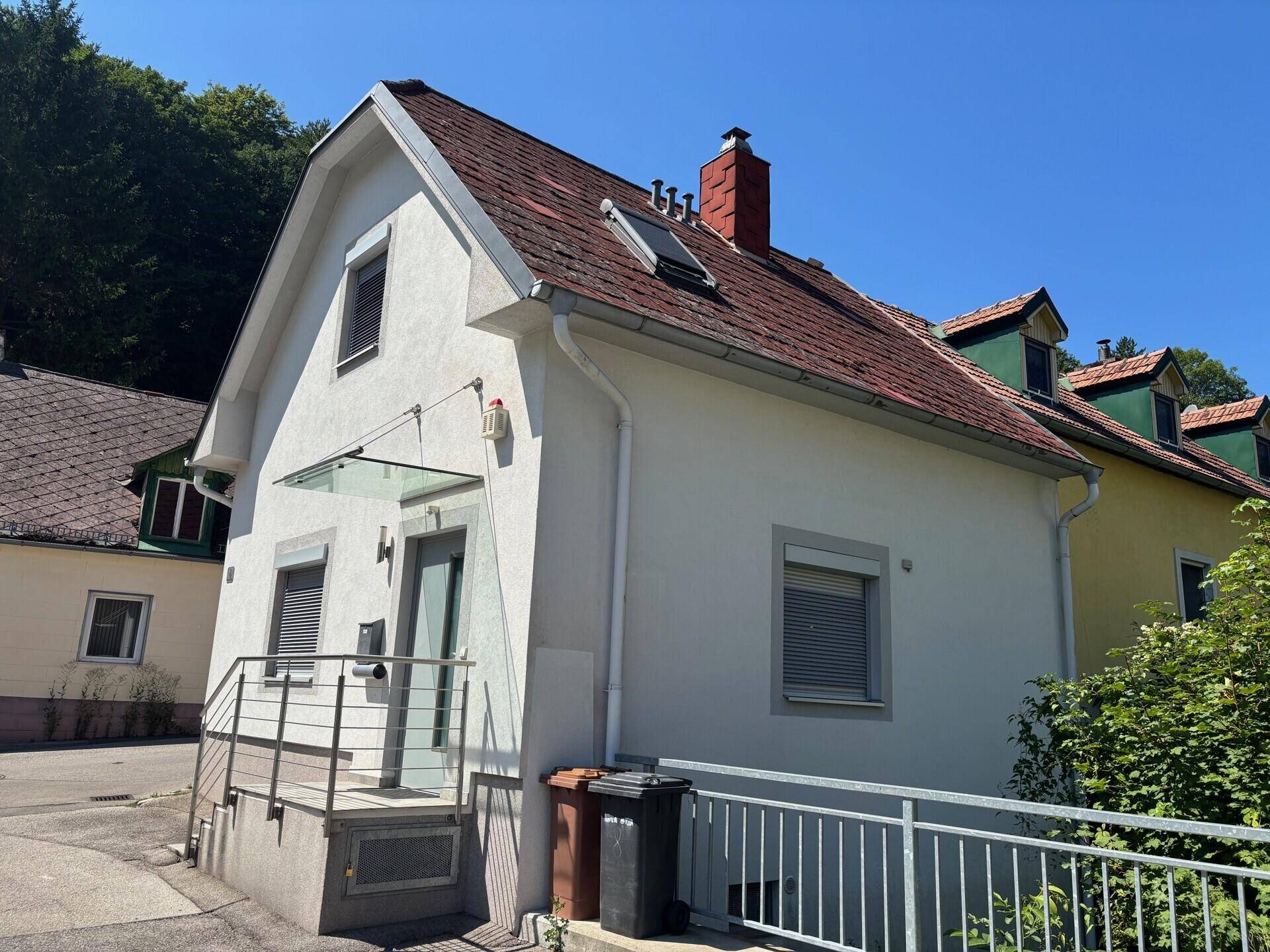 Seitenansicht eines Einfamilienhauses mit rotem Ziegeldach und Rollläden an den Fenstern.