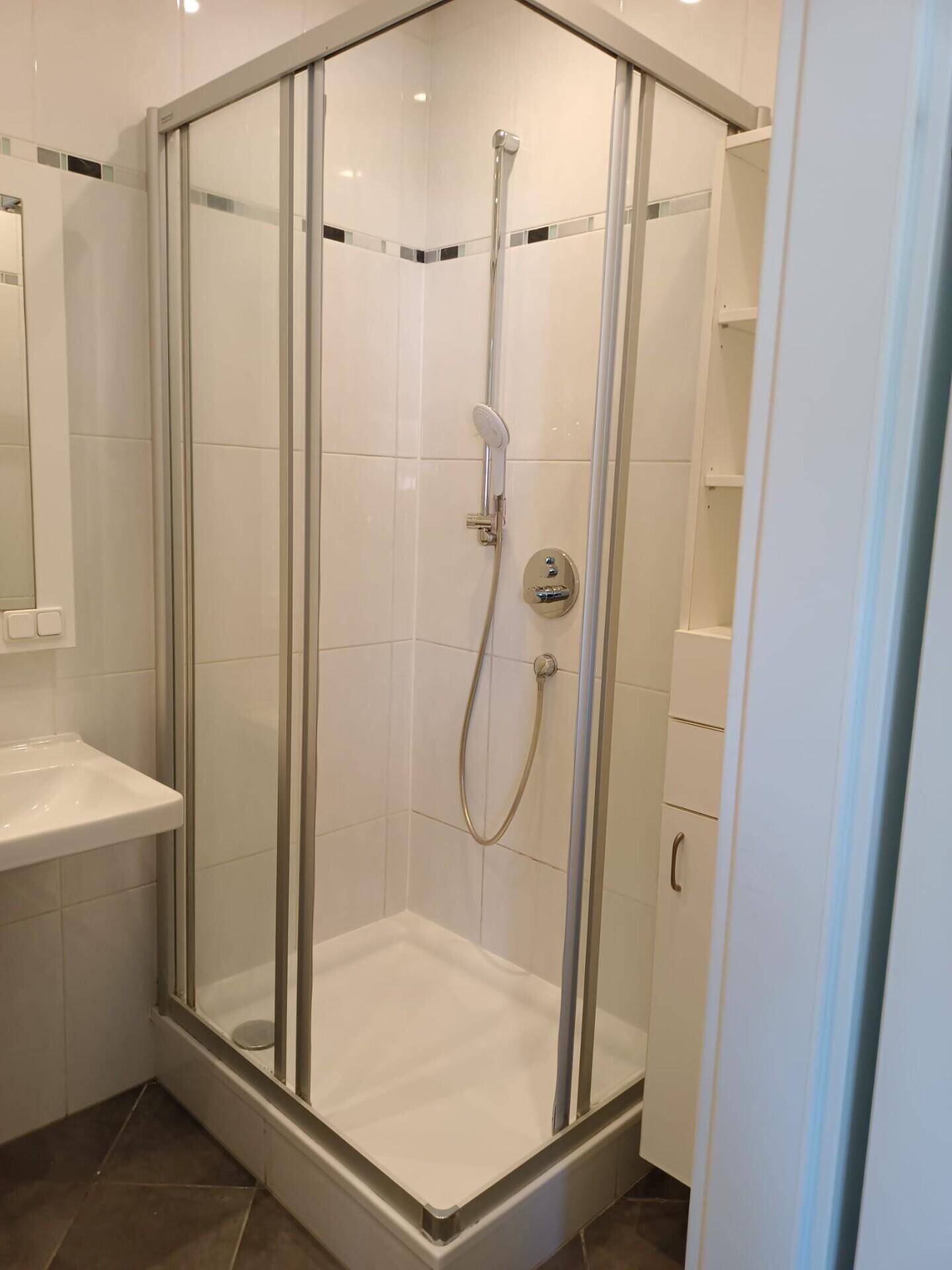 Modern geflieste Dusche mit Glasabtrennung und weißem Fliesenmuster im Badezimmer.