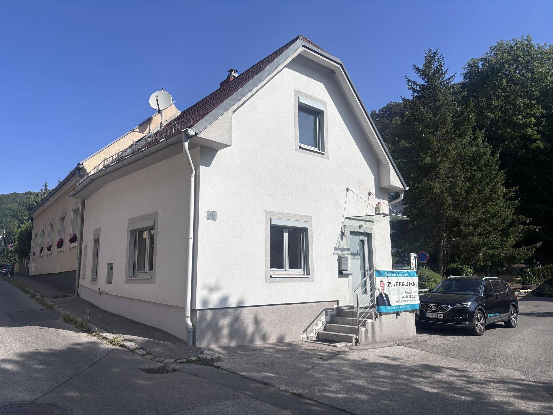 Ansicht des Einfamilienhauses von der Straße mit umliegender Vegetation und klarem Himmel.
