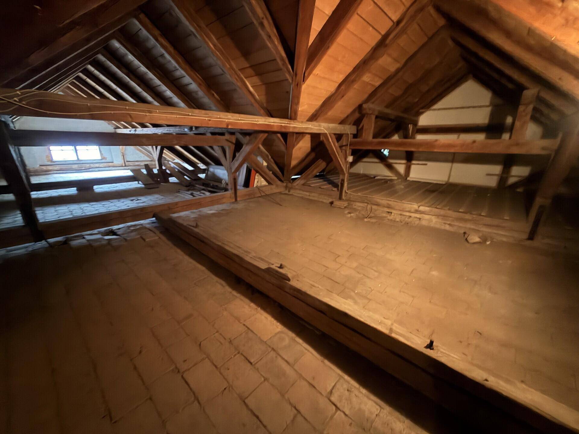 Geräumiger Dachboden mit sichtbaren Holzbalken und Ziegelboden, der viel Stauraum bietet.