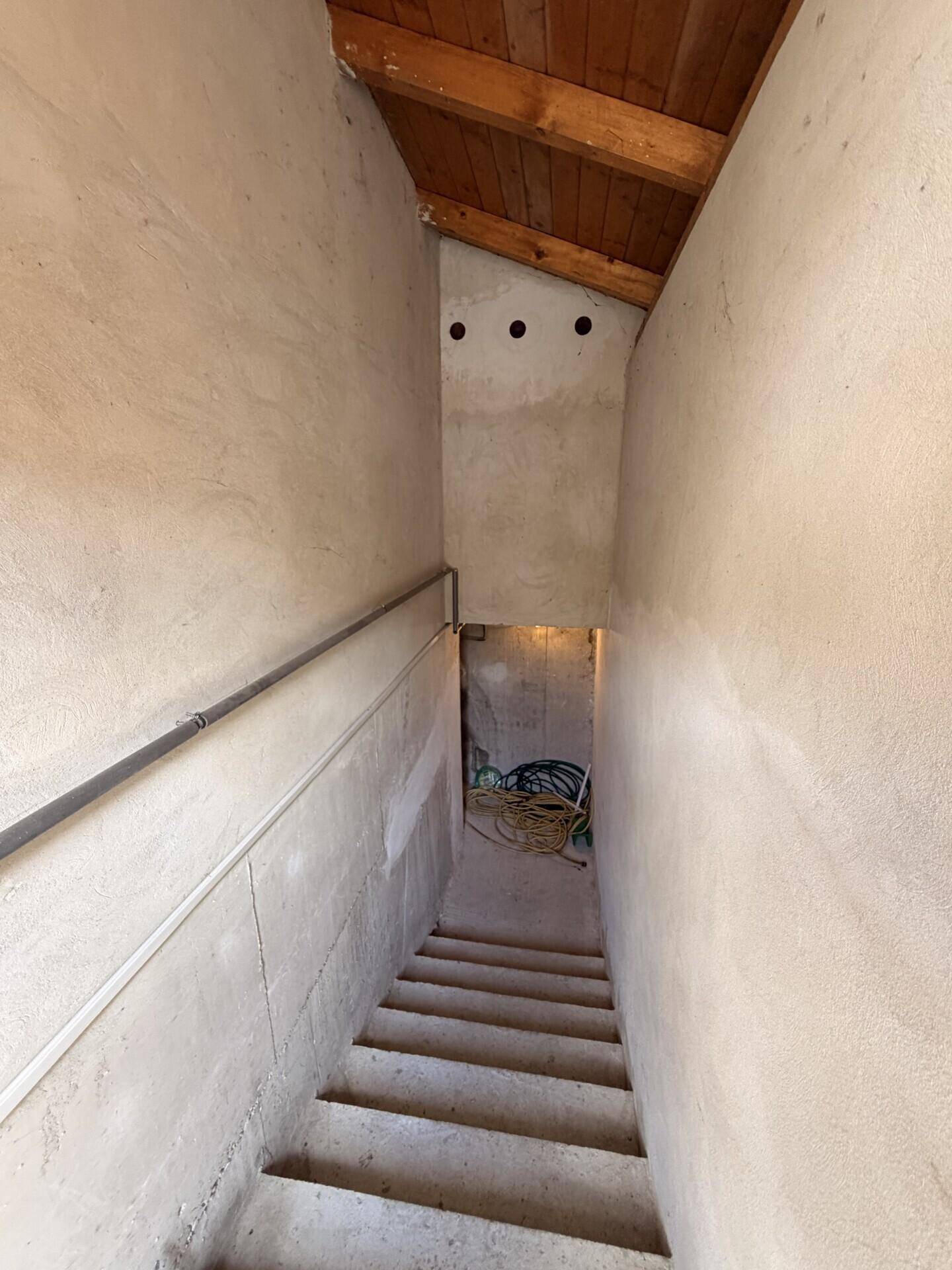 Schlichter Treppenabgang zum Keller mit Betonstufen und einem einfachen Geländer.