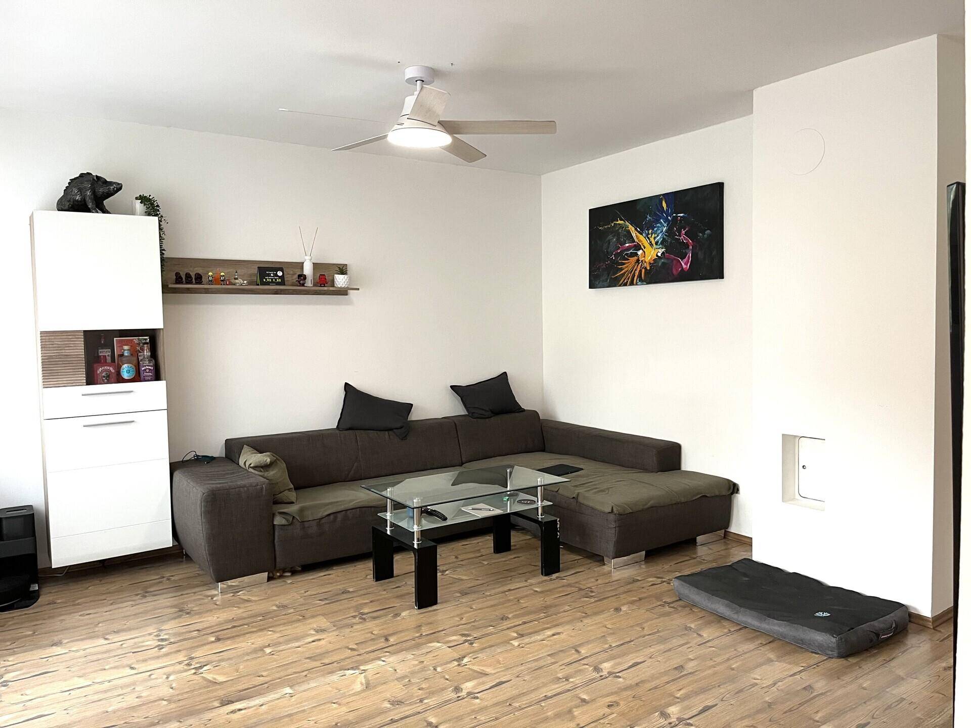 Geräumiges Wohnzimmer mit großem Ecksofa, Couchtisch und Deckenventilator für angenehmes Klima.