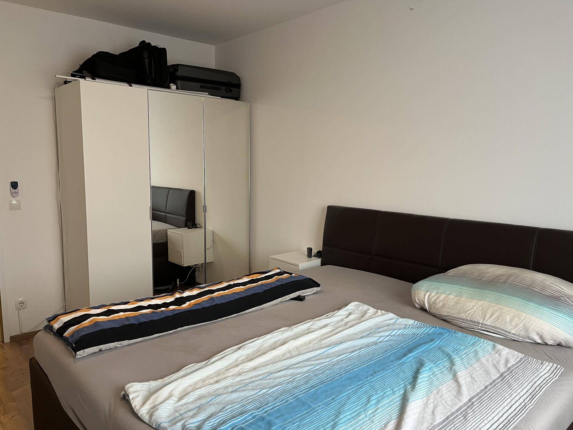 Schlafzimmer mit großem Doppelbett und einem geräumigen Kleiderschrank mit Spiegeltüren.