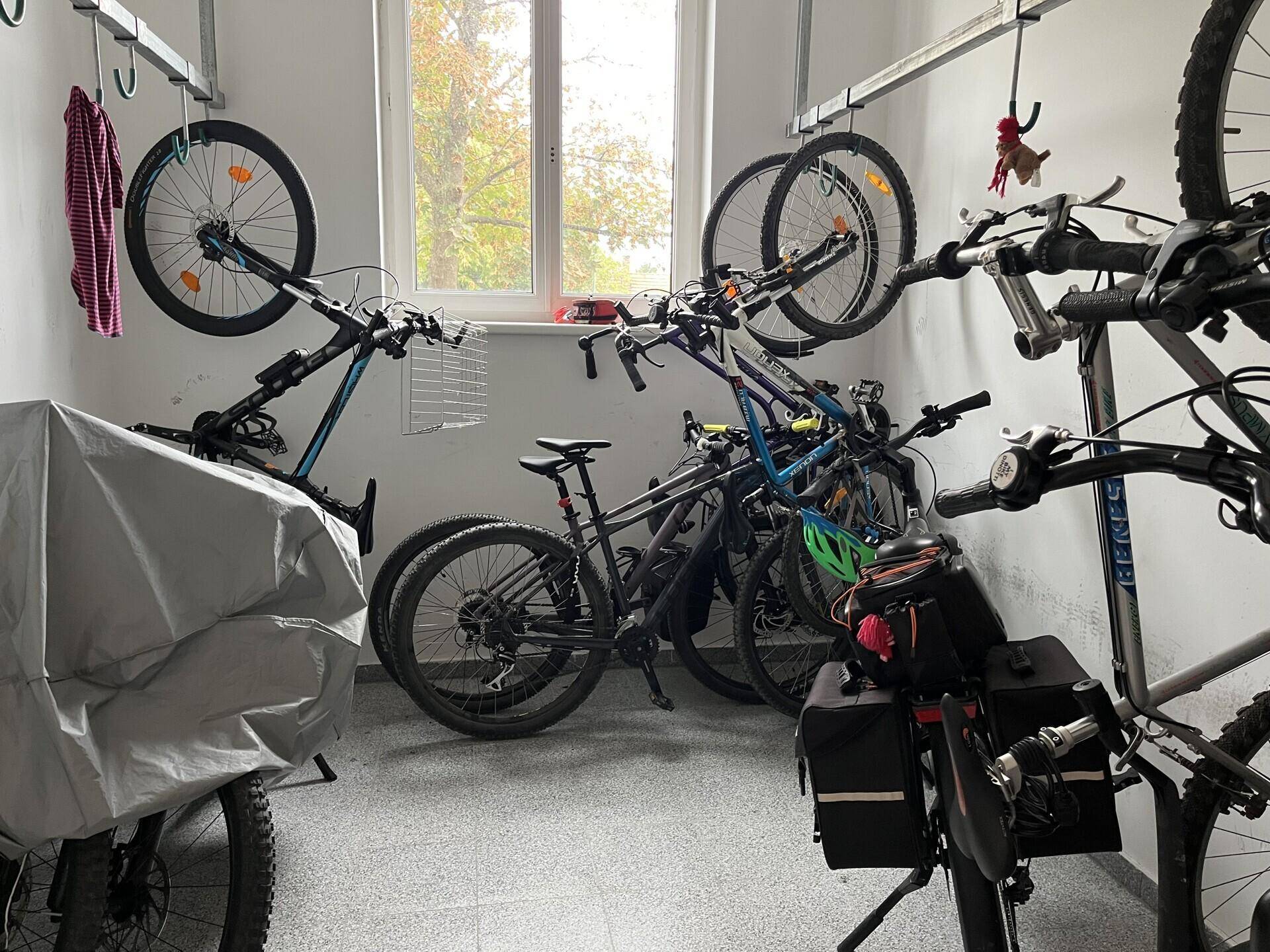 Fahrradraum mit mehreren Fahrrädern auf Wandhalterungen und einem Fenster.