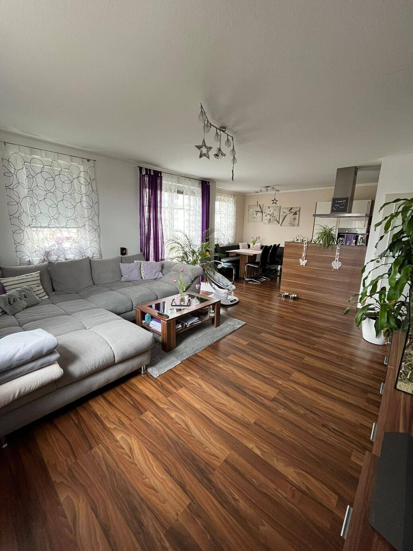 Geräumiger Wohn-Essbereich mit großem Ecksofa, Holzboden und Essbereich im Hintergrund.