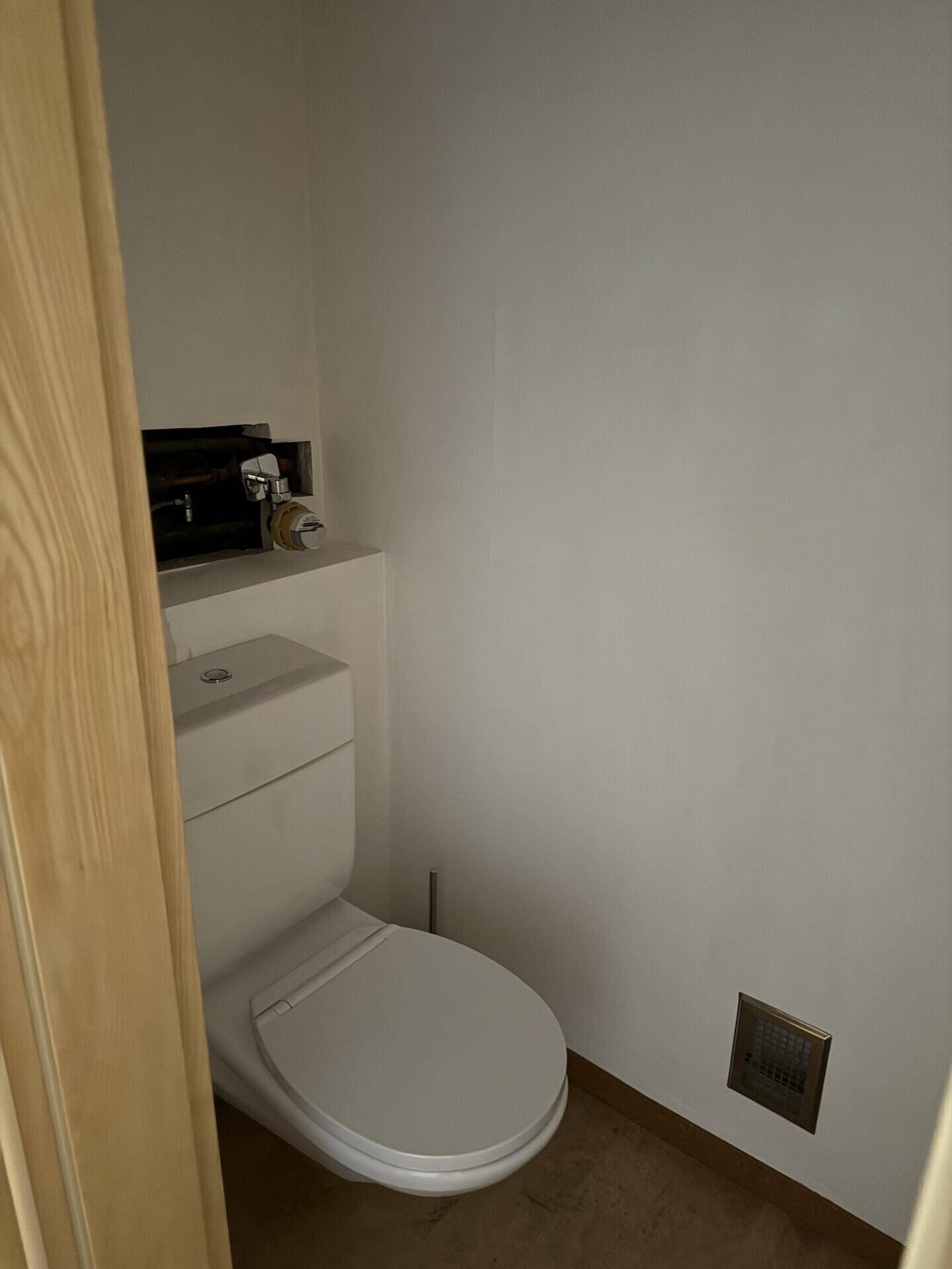 Kleines Gäste-WC mit weißer Toilette und einfacher Ausstattung.