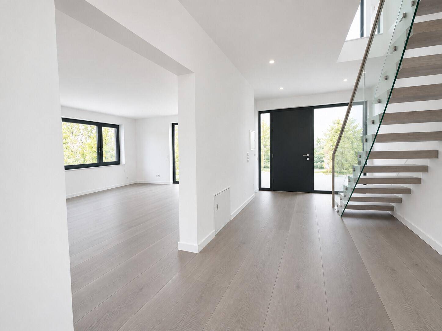 Moderner Eingangsbereich mit heller Holztreppe und offenem Zugang zu weiteren Räumen.