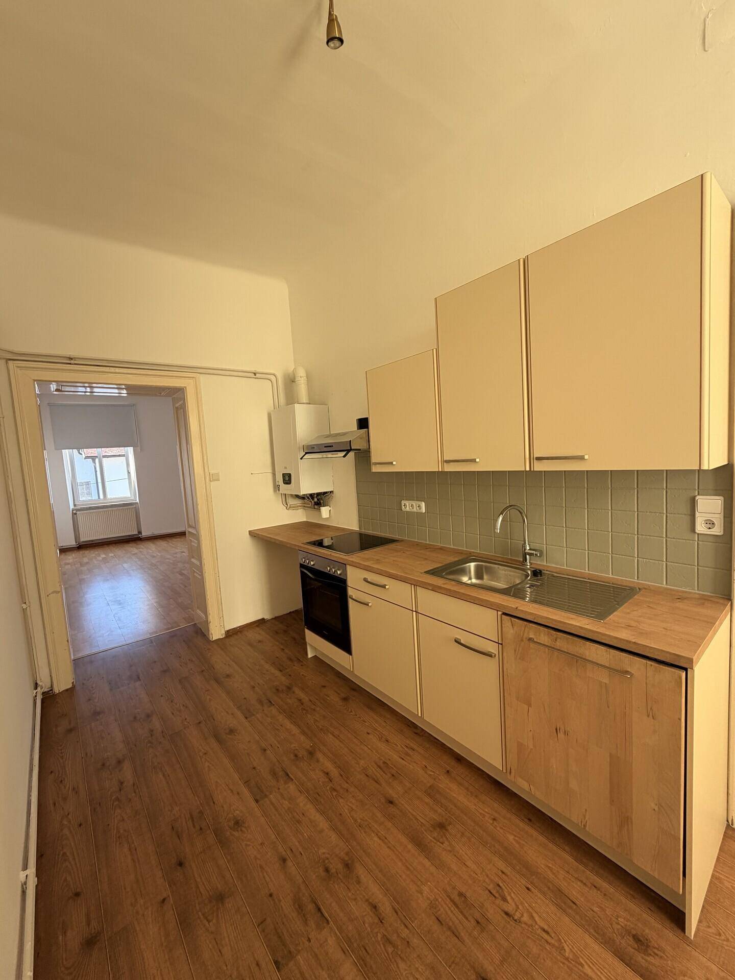 Funktionale Küche mit hellen Schränken, Holzarbeitsplatte und Geräten, bereit zum Kochen.