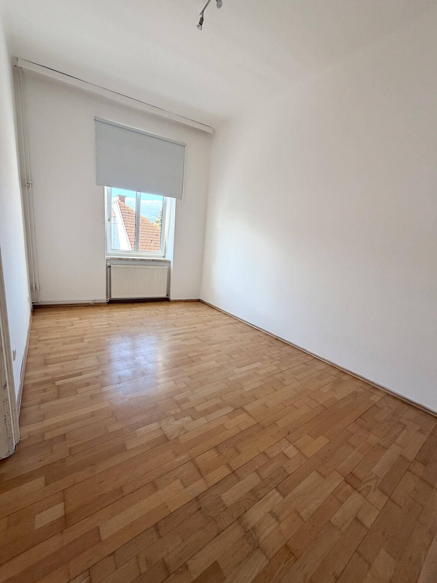 Gemütliches, helles Zimmer mit Parkettboden und einem Fenster, perfekt als Schlaf- oder Arbeitszimmer.