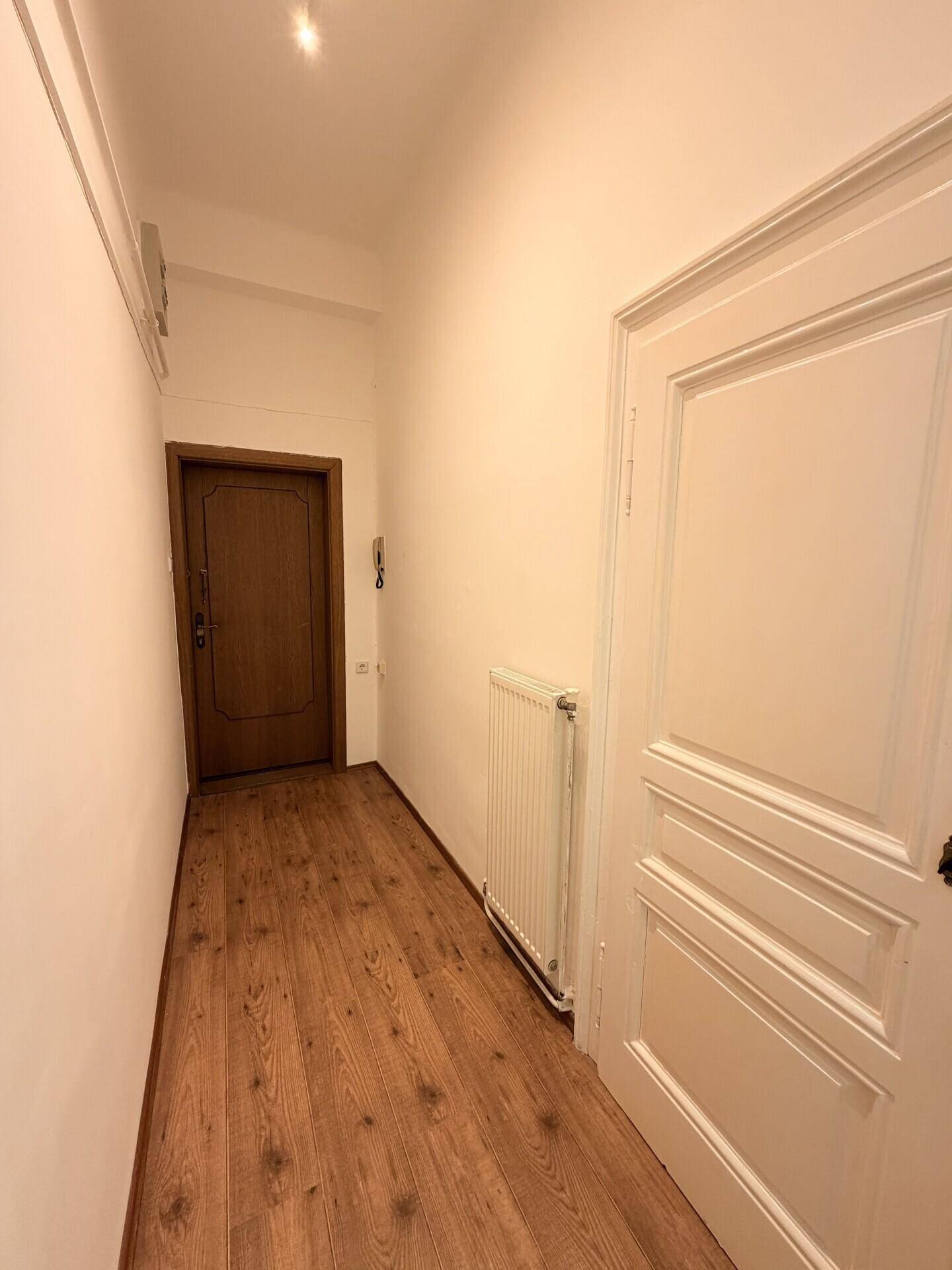 Heller Flur mit Laminatboden und weißen Wänden, verbindet die verschiedenen Räume der Wohnung.