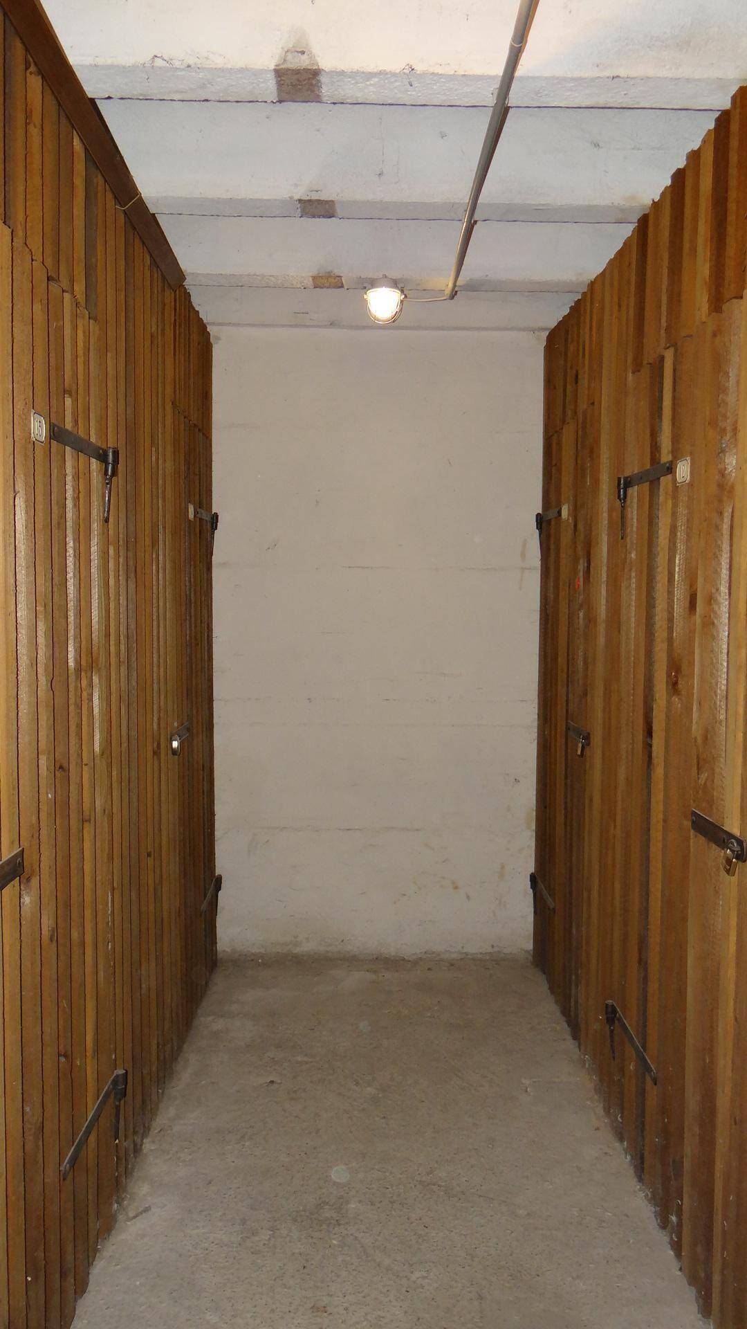 Kellerabteil mit Holzwänden und Betonboden, ideal für zusätzlichen Stauraum.