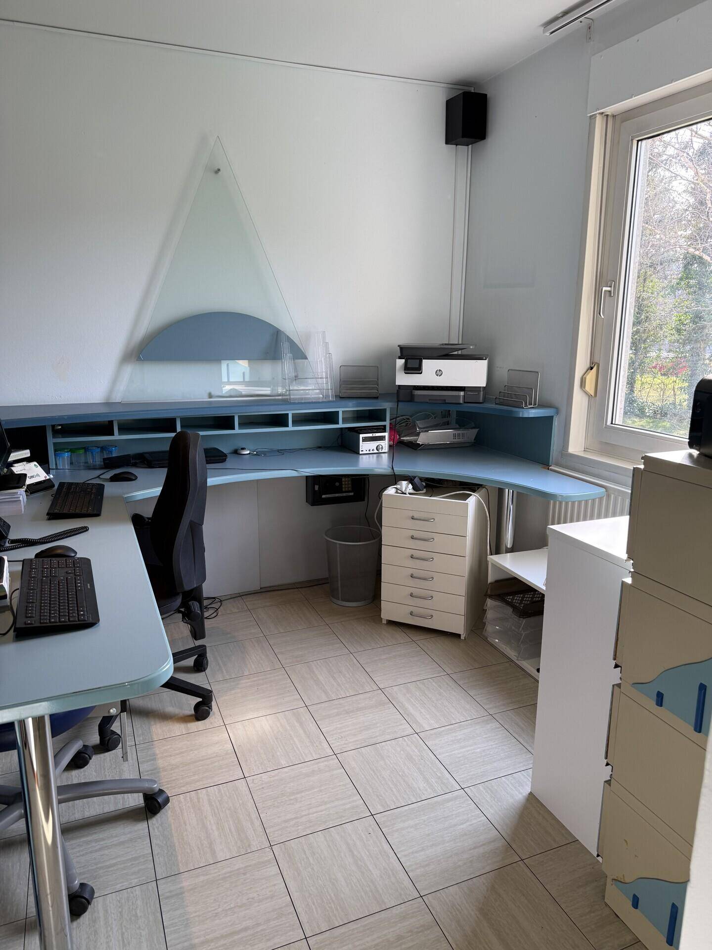 Büroarbeitsplatz mit Schreibtisch, Computer und einem Fenster, das Tageslicht hereinlässt.