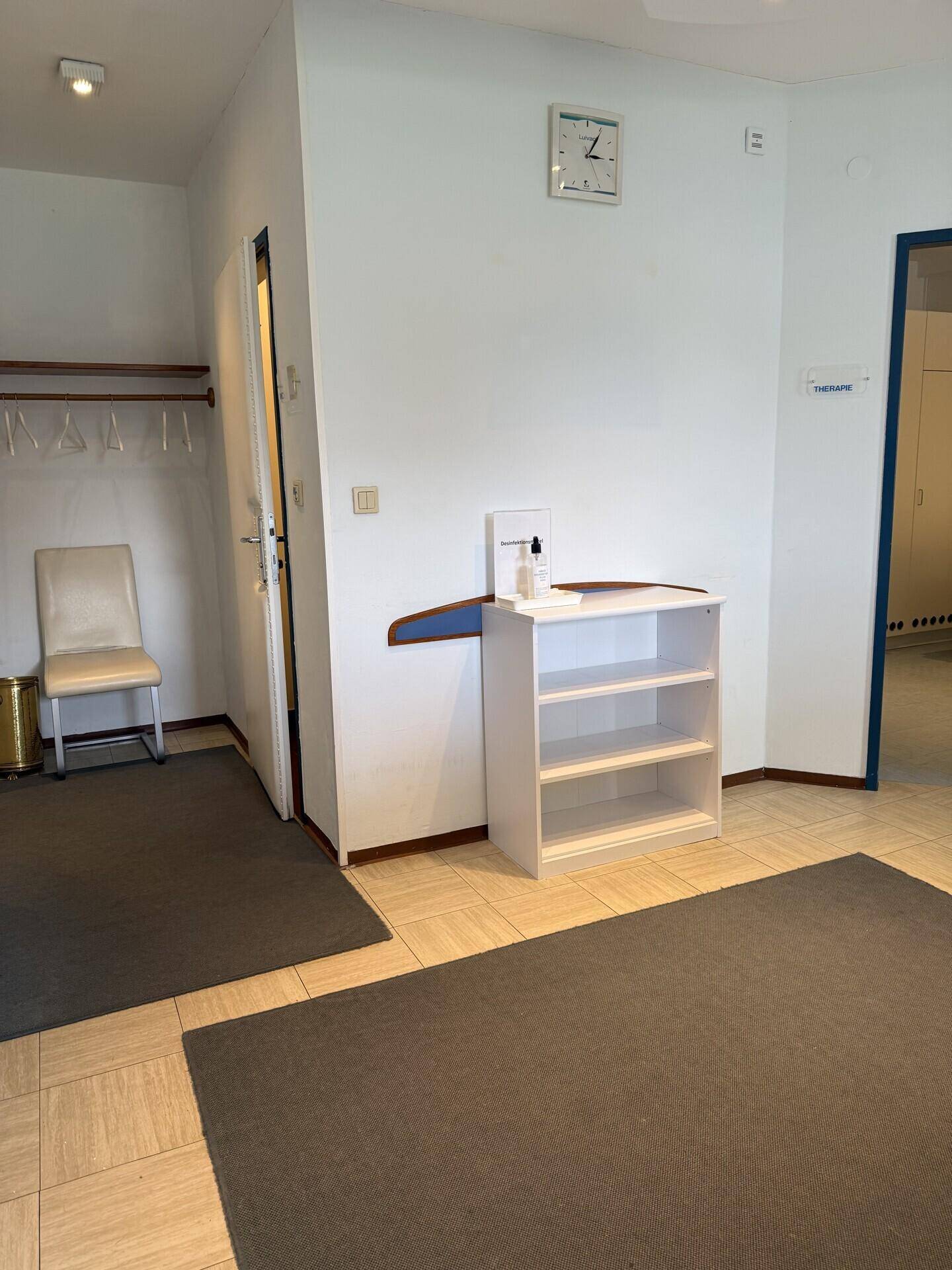 Eingangsbereich oder Flur mit Garderobe, Regal und Teppichläufern auf dem Fliesenboden.