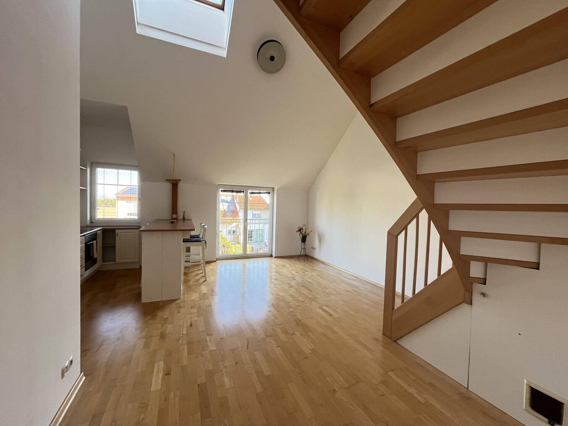 Geräumiger Wohnbereich mit offener Küche, Holztreppe und viel Tageslicht.